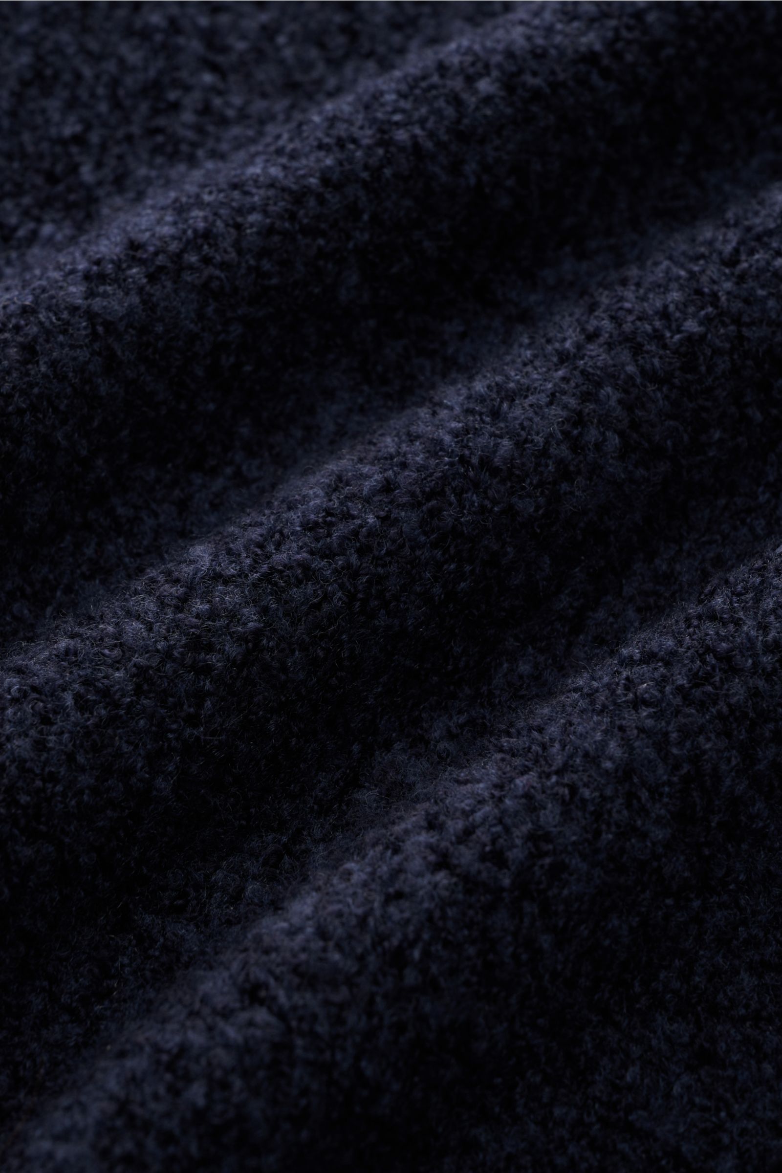 Close-up image of navy boucle knit fabric showing texture and softness, photographed from a top-down perspective. The 04651/ A trip in a bag Half-zip jumper 'Grainy' navy features a blend of wool and microfibre, soft feel, medium-fine knit, regular fit, h