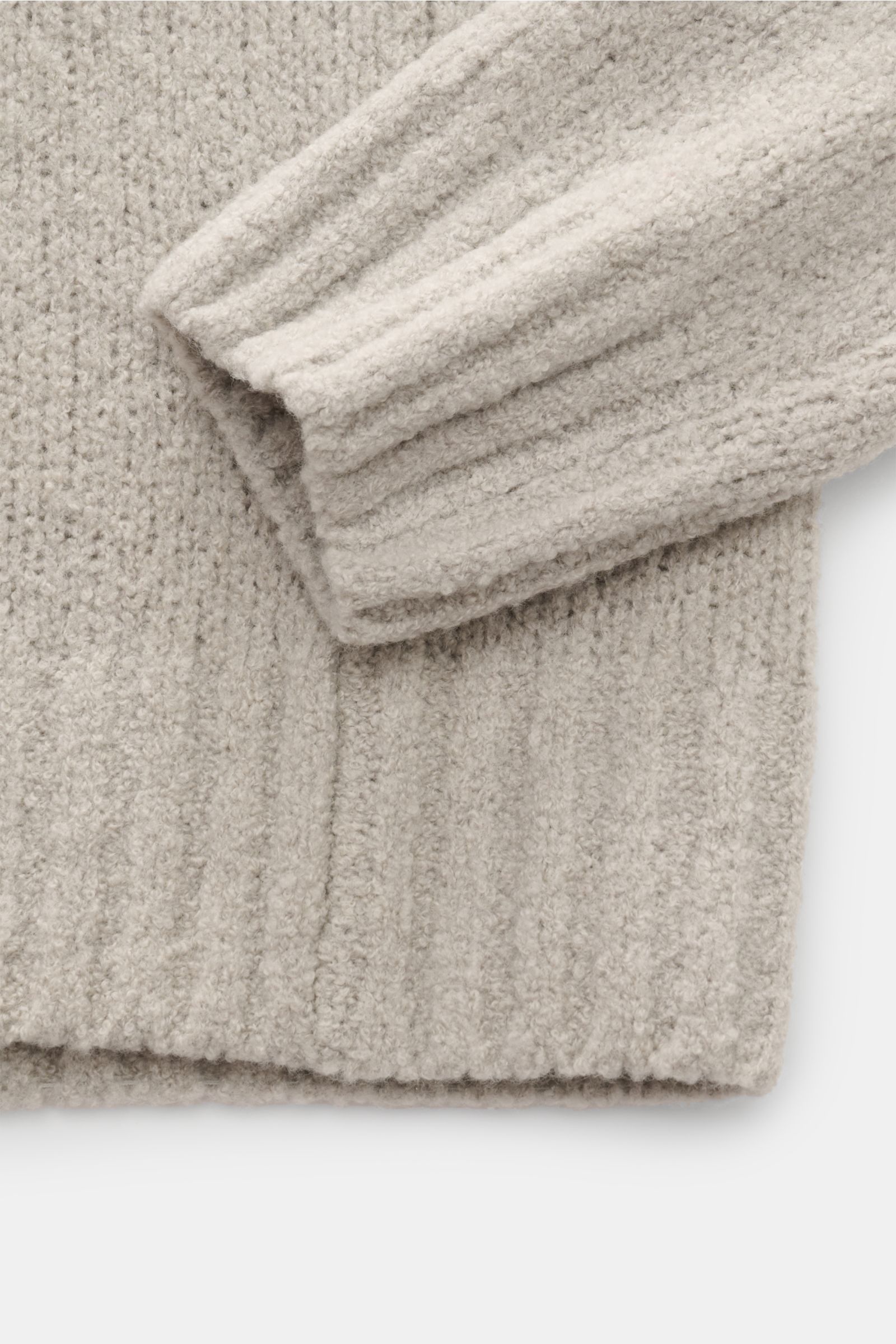 Nahaufnahme von Bündchen und Ärmel eines 04651/ A trip in a bag Troyer 'Grainy' sand aus Boucléstrick, mittelfeinem Strickbild, Regular Fit, Mix aus Wolle und Microfaser, weicher Griff, hoher Rippstrickkragen mit Zipper, breite Rippbündchen, fotografiert 