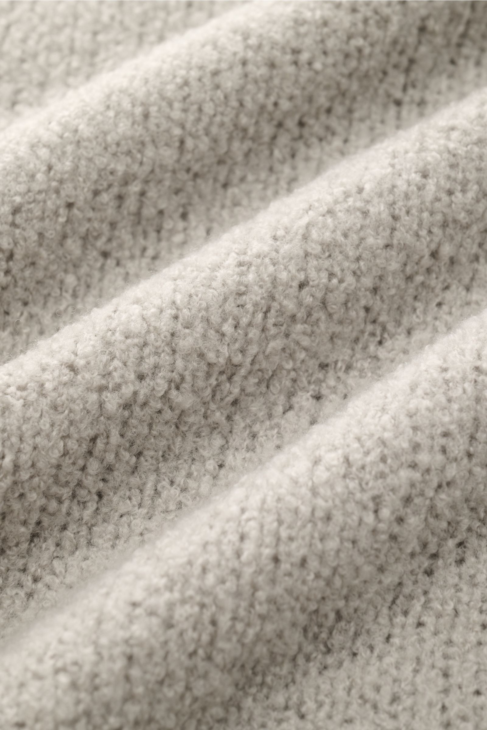 Nahaufnahme des Boucléstricks mit mittelfeinem Strickbild und weichem Griff, Mix aus Wolle und Microfaser des 04651/ A trip in a bag Troyer 'Grainy' sand.