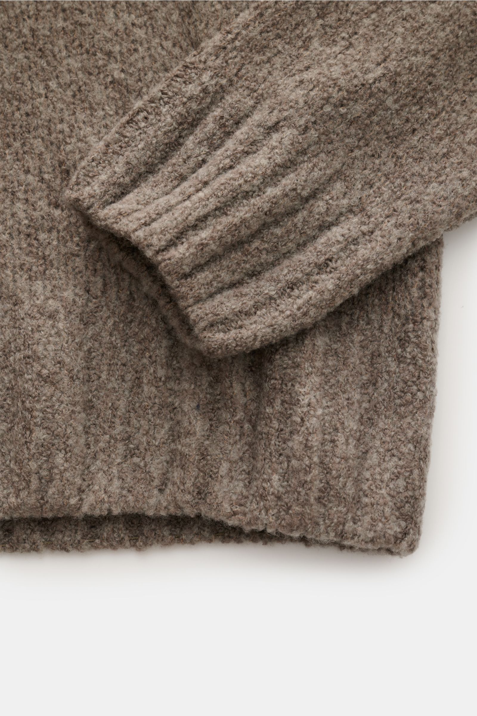 Nahaufnahme von Ärmel und Bund des 04651/ A trip in a bag Troyer 'Grainy' taupe, Boucléstrick, mittelfeines Strickbild, Mix aus Wolle und Microfaser, weicher Griff, Regular Fit, hoher Rippstrickkragen mit Zipper, breite Rippbündchen.