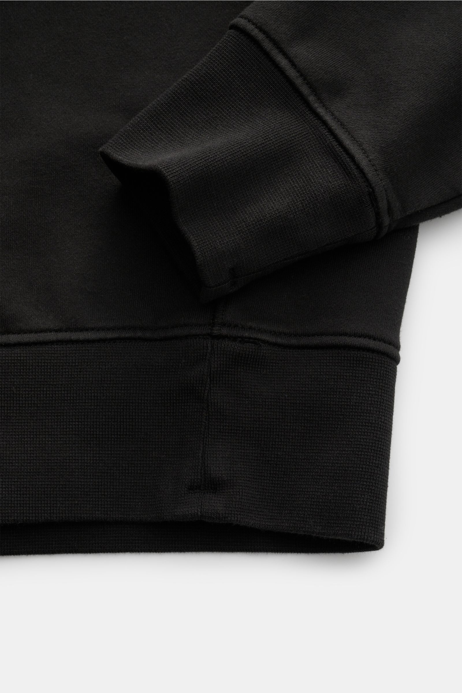 Close-up view of the cuff and hem of the Stone Island Sweat-Troyer 'Basic Sweat' schwarz, showing its soft cotton fabric and ribbed details.

Sportives Essential: Der Sweat-Troyer von STONE ISLAND überzeugt als legeres Basic Piece und wird zum unverzic