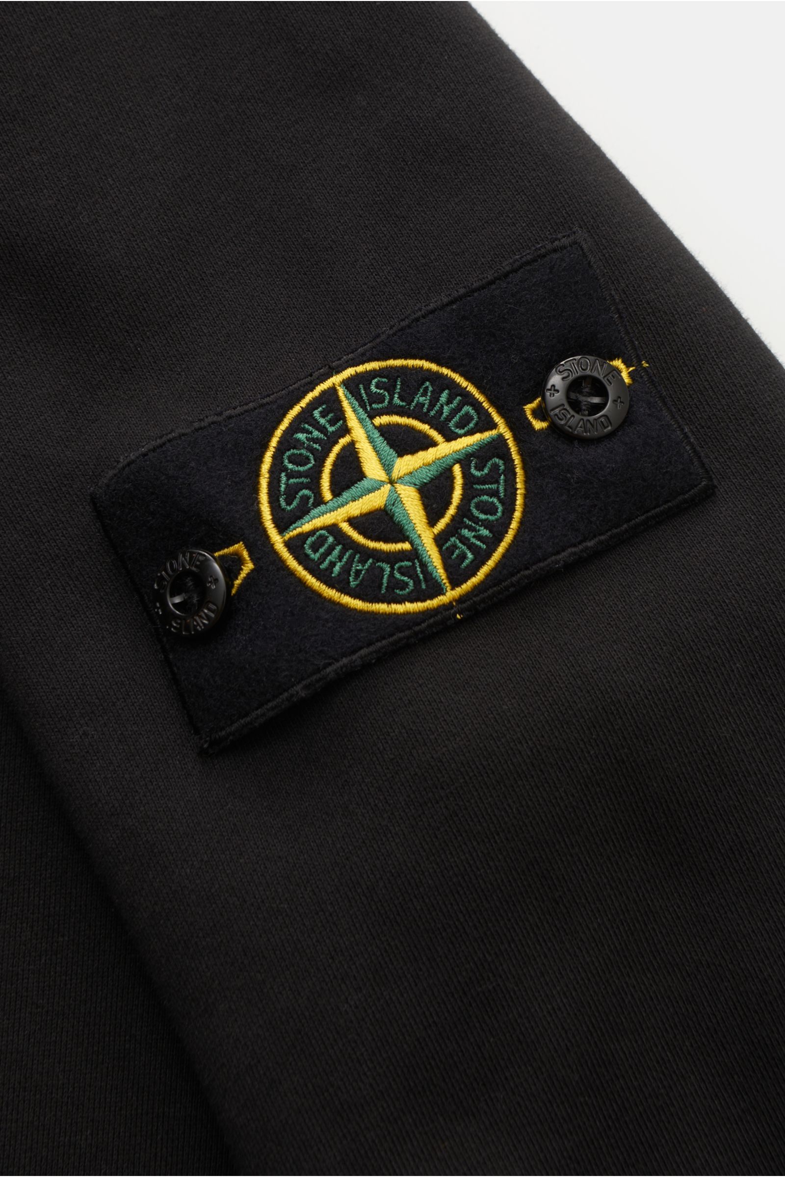 Close-up view of the Stone Island Troyer 'Basic Sweat' schwarz showing the black fabric and iconic compass badge on the upper arm.

Sportives Essential: Der Sweat-Troyer von STONE ISLAND überzeugt als legeres Basic Piece und wird zum unverzichtbaren Be