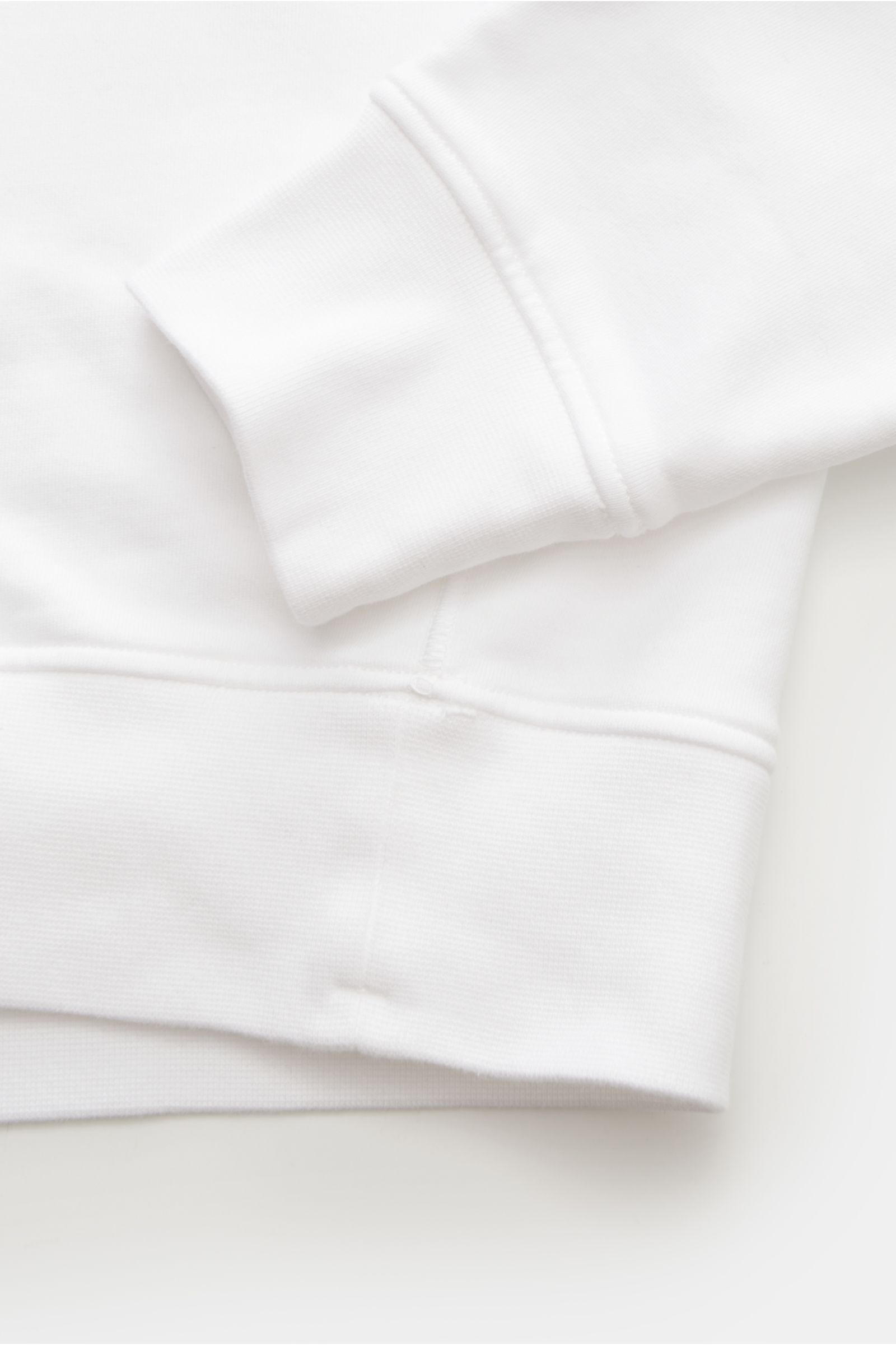 Close-up of the cuff and hem from the side of the Stone Island Troyer 'Basic Sweat' weiß in white cotton fabric

Sportives Essential: Der Sweat-Troyer von STONE ISLAND überzeugt als legeres Basic Piece und wird zum unverzichtbaren Begleiter für urbane 