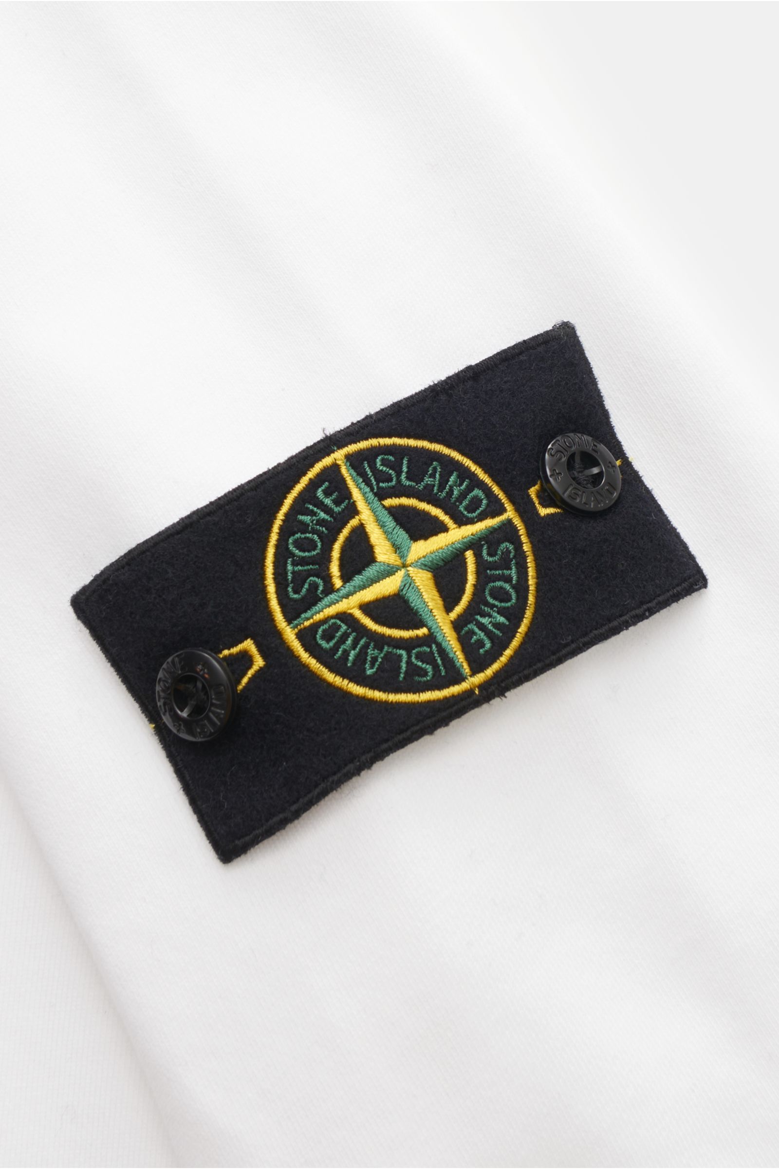 Close-up of the black compass badge on the sleeve of the Stone Island Troyer 'Basic Sweat' weiß, photographed from a top-down perspective.

Sportives Essential: Der Sweat-Troyer von STONE ISLAND überzeugt als legeres Basic Piece und wird zum unverzicht