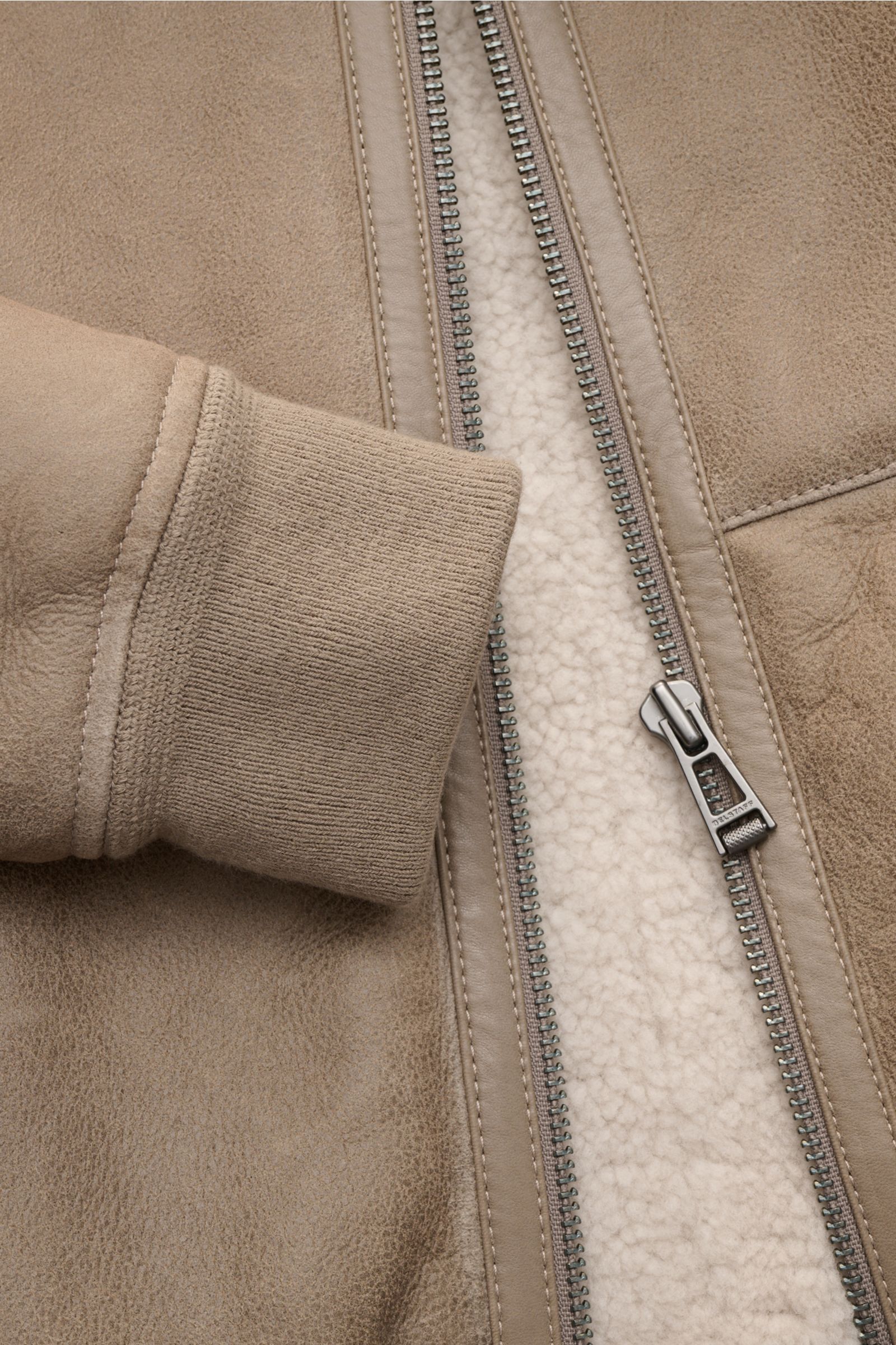 Close-up front view of Belstaff Lammfell-Blouson 'Trace' khaki showing half-oiled English premium lamb leather, ribbed cuff, smooth leather details, robust zipper with tonal stitching, and soft lambswool lining. Der Lammfellblouson 'Trace' von BELSTAFF