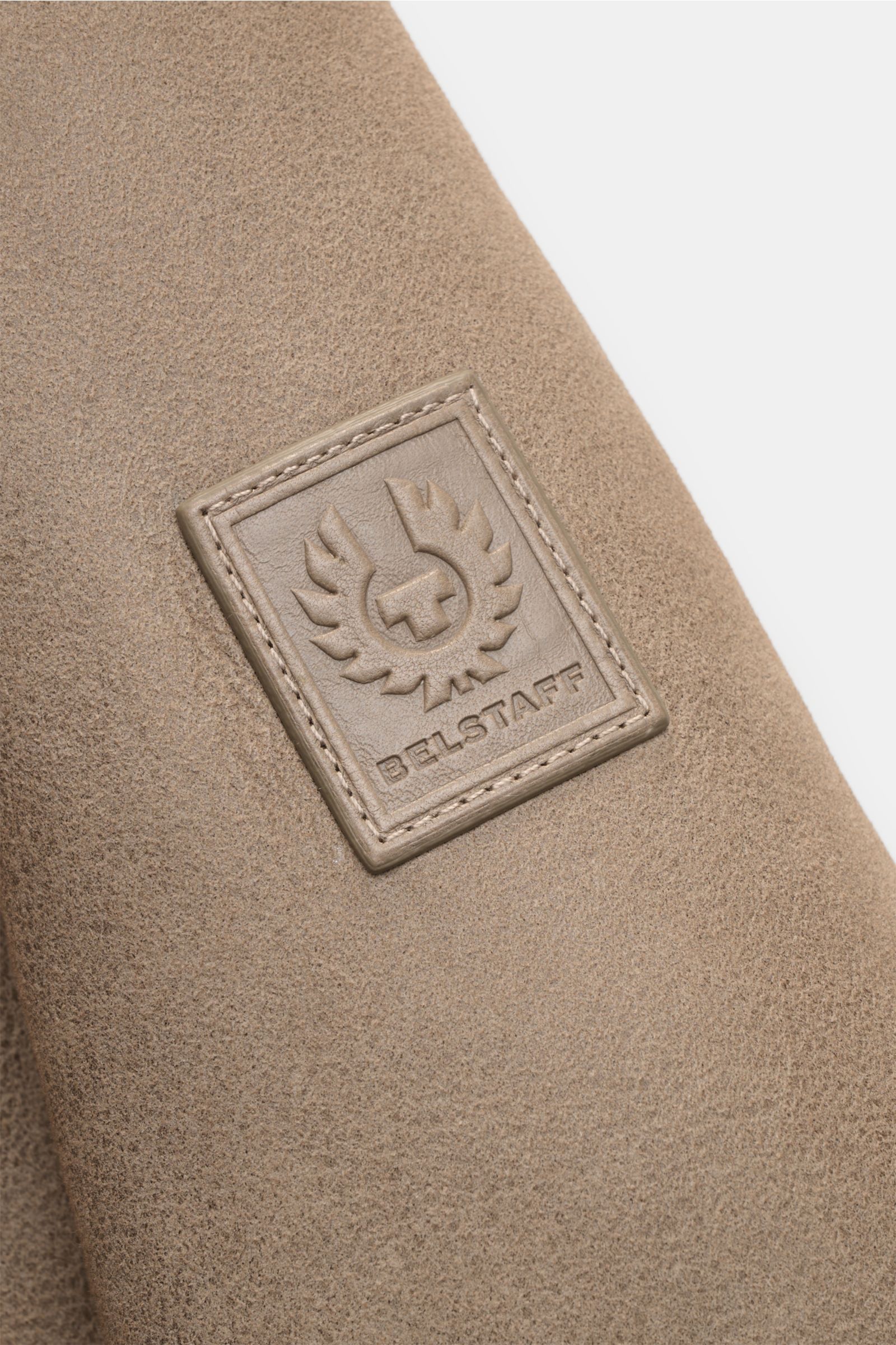 Close-up of the Belstaff Lammfell-Blouson 'Trace' khaki showing the embossed tonal Belstaff logo patch on suede leather, photographed from the front sleeve angle.

Der Lammfellblouson 'Trace' von BELSTAFF vereint authentisches Design mit markanter Mate