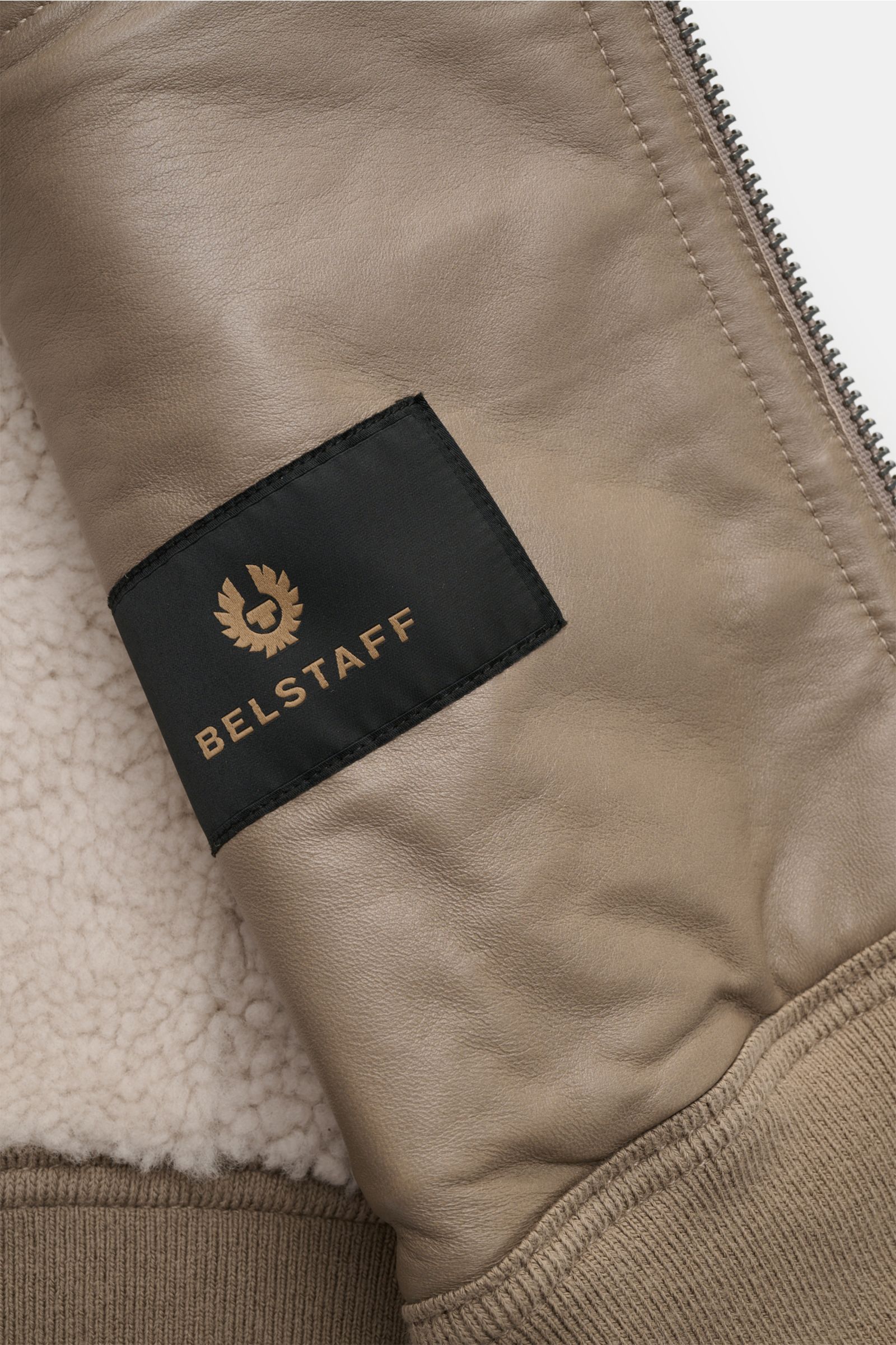 Close-up view of the sleeve of the Belstaff Lammfell-Blouson 'Trace' khaki, showing premium English lamb leather with a black BELSTAFF logo patch, rib-knit cuff, and soft lambswool interior. The Lammfellblouson 'Trace' by BELSTAFF combines authentic desig