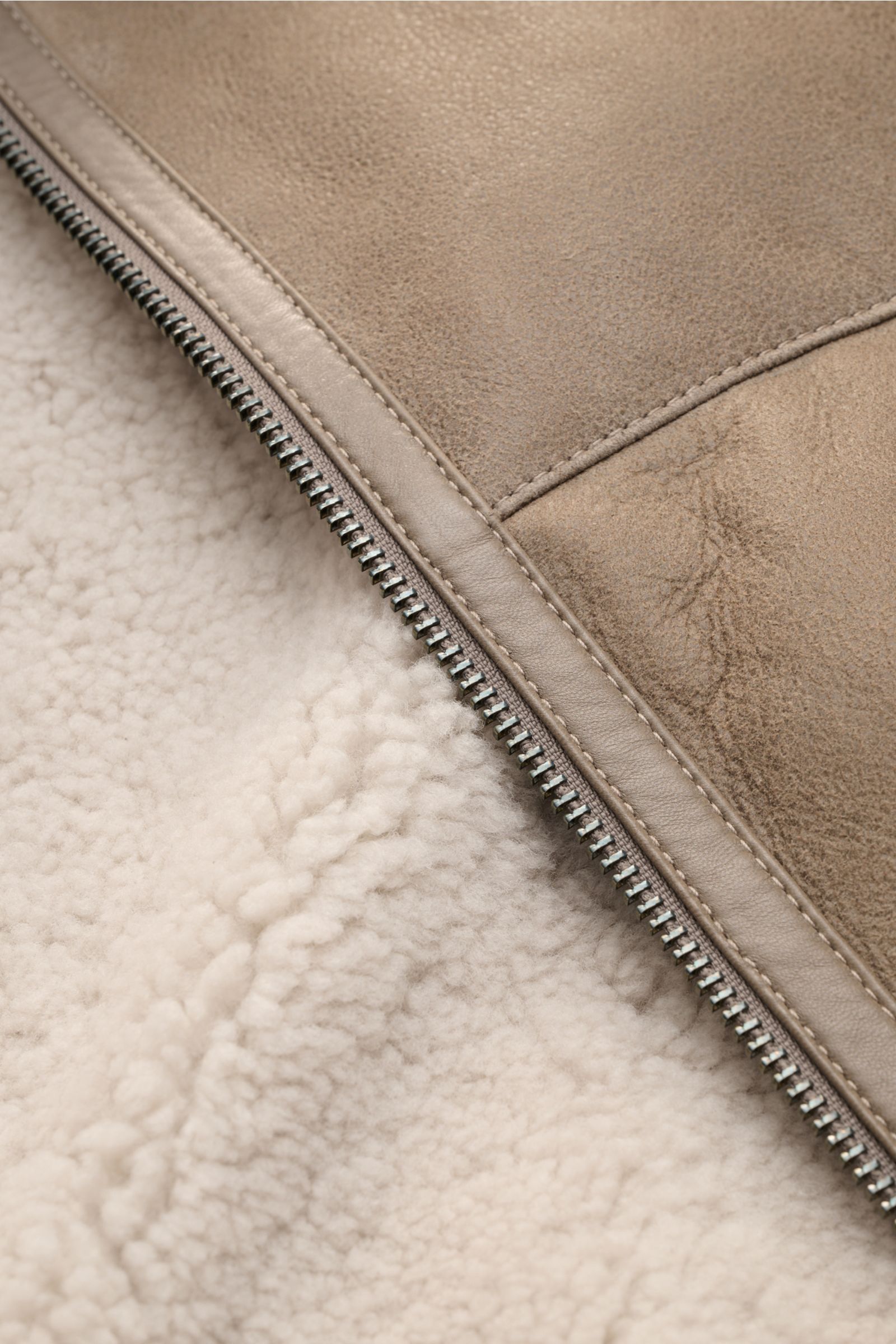 Close-up of the Belstaff Lammfell-Blouson 'Trace' khaki showing premium English lamb leather with a rustic semi-oiled finish, soft lambswool inside, and a sturdy zipper, photographed from a side angle. Der Lammfellblouson 'Trace' von BELSTAFF vereint a