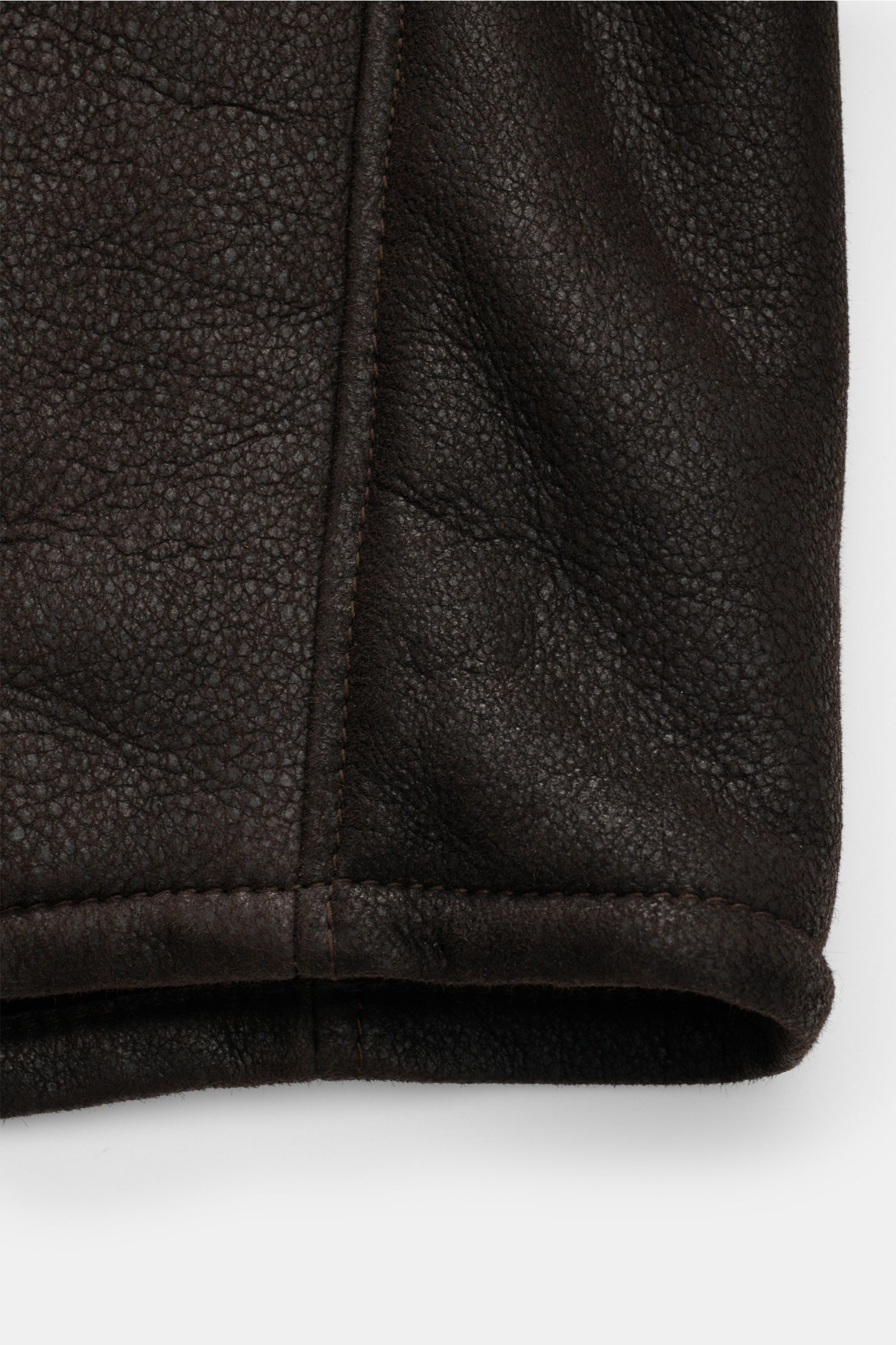 Windsor Lammfelljacke 'Aro' dunkelbraun in Slim Fit, Detailaufnahme der materialtypischen Struktur und Saumnaht aus edlem Lammfell.