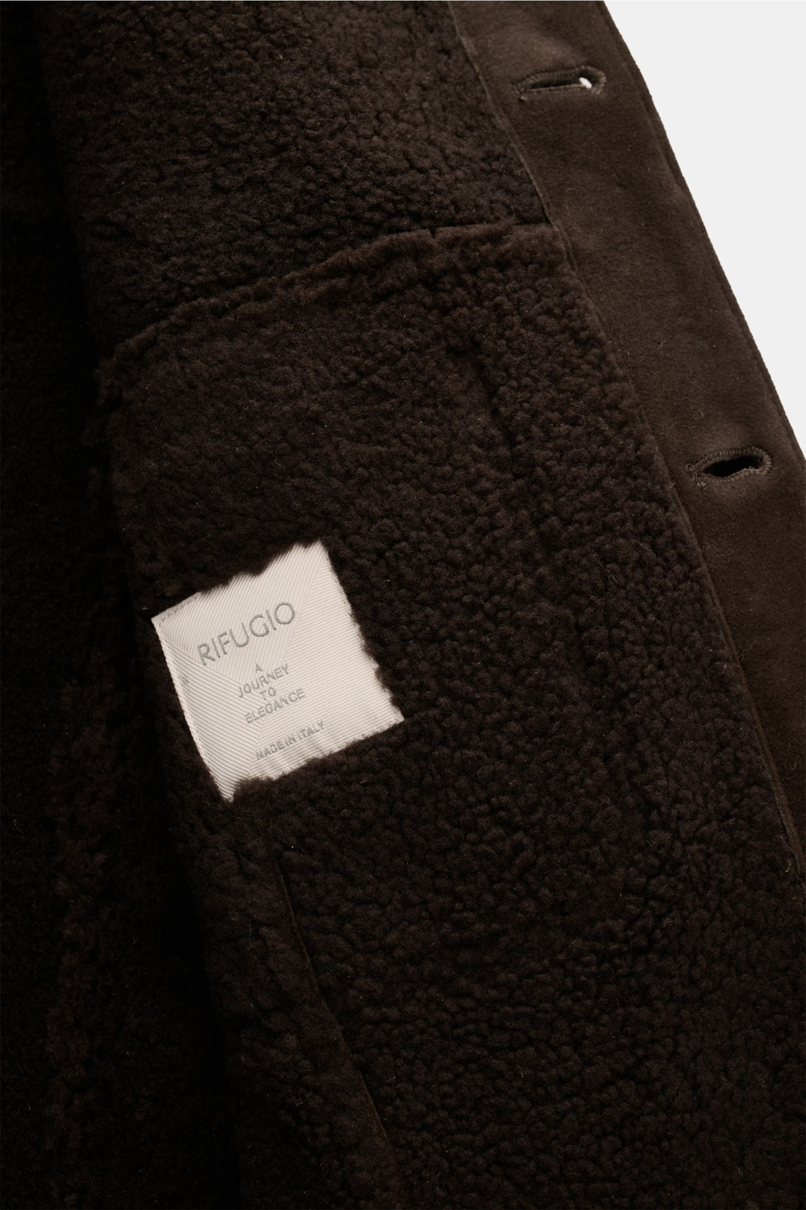 Nahaufnahme der Innenseite der Rifugio Lammfelljacke dunkelbraun aus geschmeidigem Veloursleder mit weichem Griff, Lammfellfutter, Slim Fit, sechs Knöpfen, Umlegekragen, Brusttaschen mit Patte und Manschettenärmeln.