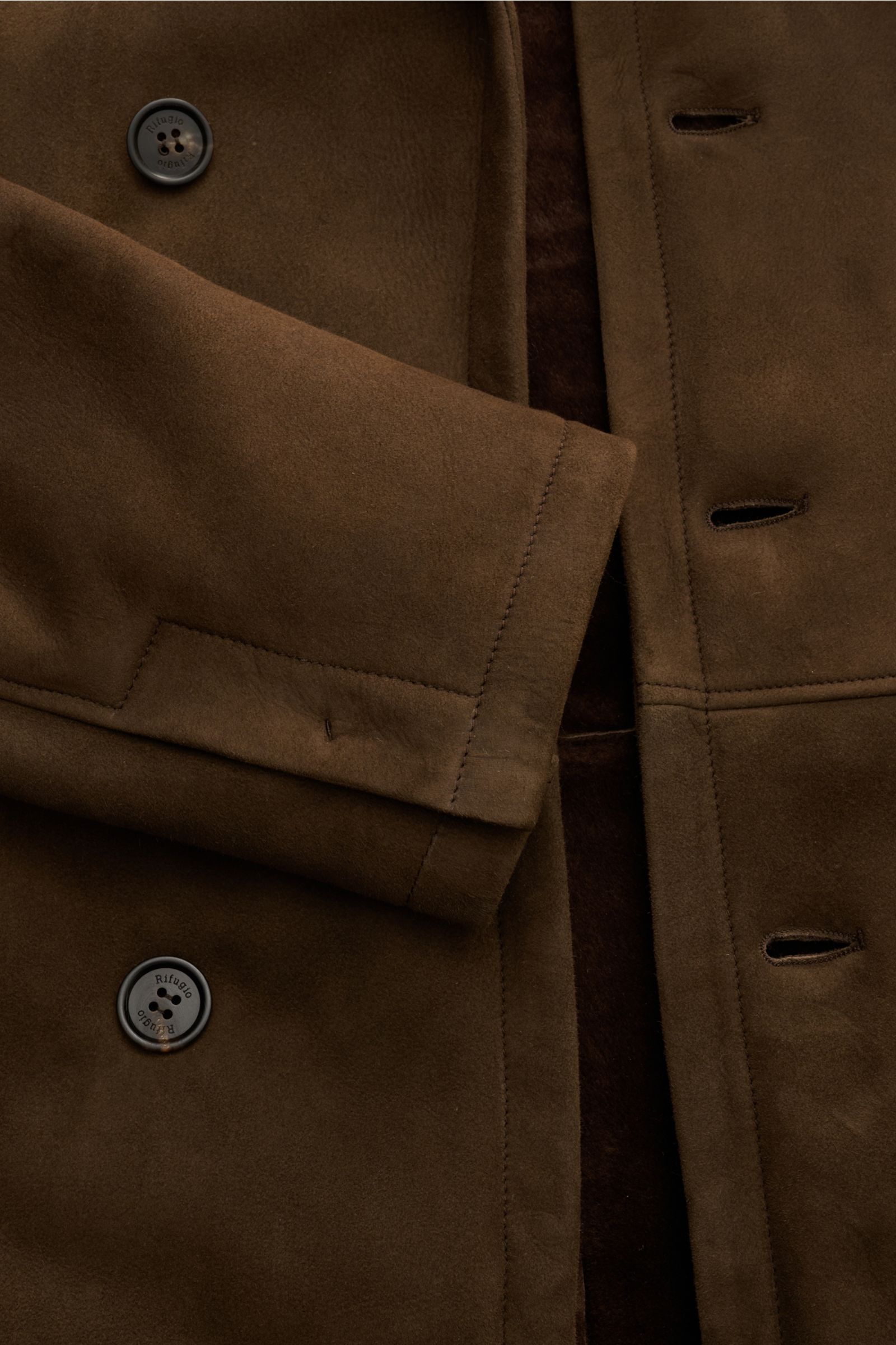 Nahaufnahme der Rifugio Lammfelljacke braun von vorne schräg oben mit sichtbarem Reverskragen, weichem Lammveloursleder, Slim Fit, Knöpfen und Ärmelabschluss mit Schlitz.