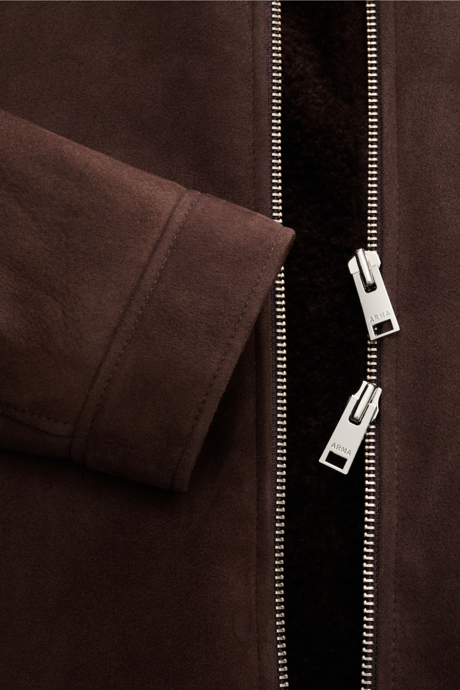 Close-up front view of the Arma Lammfelljacke 'Hara' dunkelbraun showing edles Lammveloursleder, Innenseite aus Lammfell, Slim Fit, robuster Zwei-Wege-Reißverschluss, Umlegekragen mit Lammfell, schräge Leistentaschen mit Druckknopf.