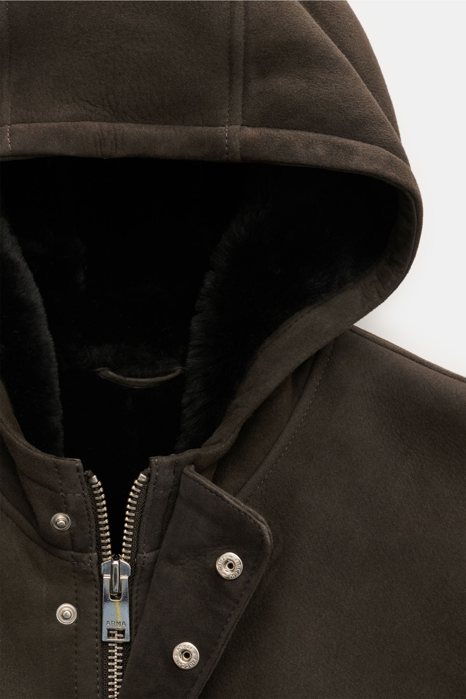 Arma Lammfellmantel 'Mias' dunkelbraun, Nahaufnahme Kapuze mit schwarzem Fell, Zwei-Wege-Reißverschluss und Druckknöpfen, samtiges Lammvelours.