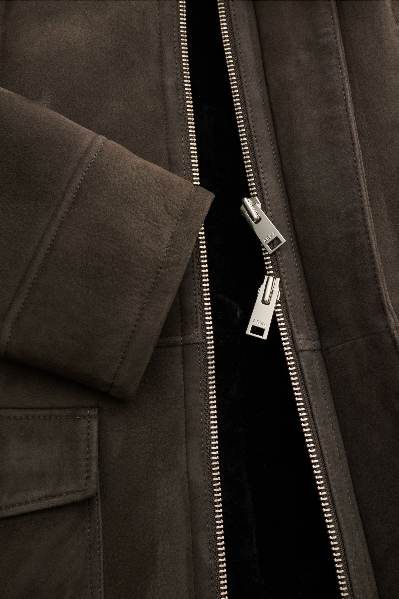 Arma Lammfellmantel 'Mias' dunkelbraun in Nahaufnahme von vorne, samtiges Lammvelours, sichtbarer Zwei-Wege-Zipper, weiches Lammfell innen.