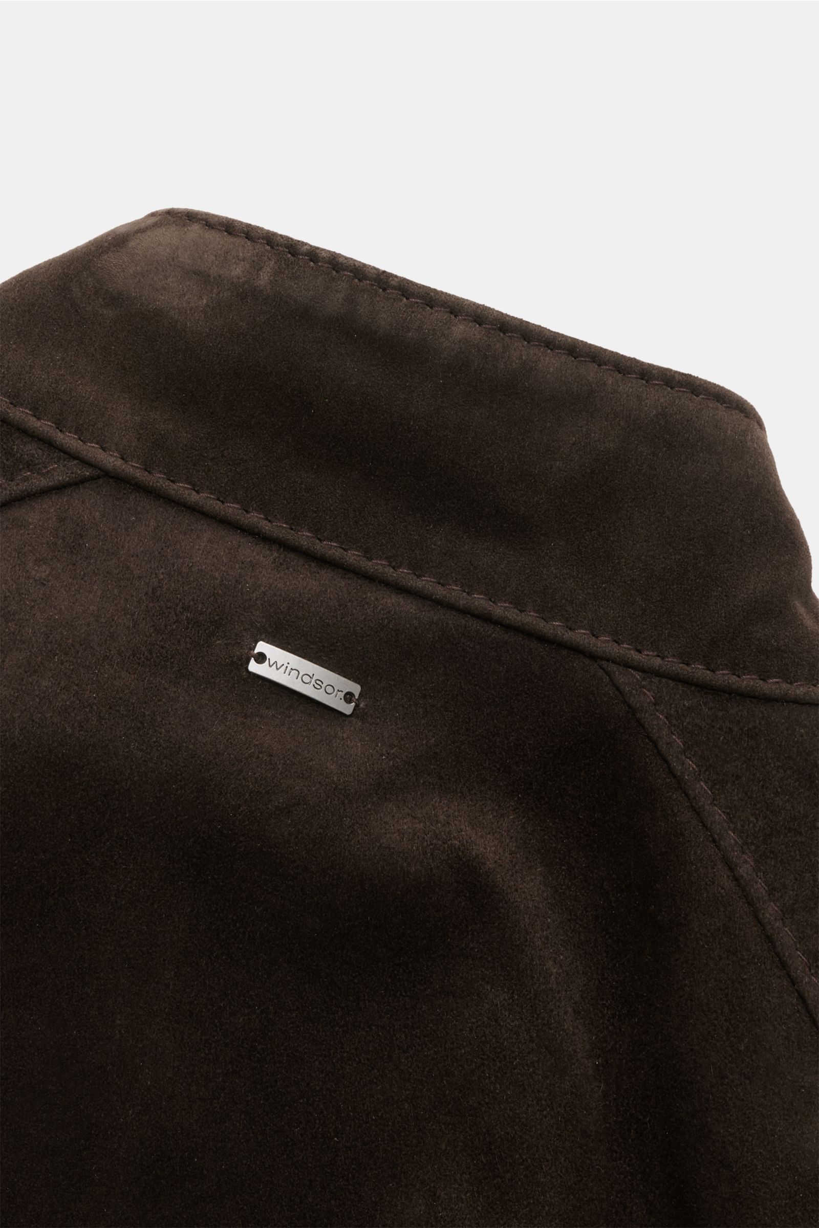 Close-up view of the back collar of the Windsor Veloursleder Blouson 'Borello' navy, showing fine velours leather texture and a small metal 'windsor' logo. Geschmeidiger Blouson: Die chromfrei gegerbte Lederjacke 'Borello' von WINDSOR wurde aus edlem Zieg