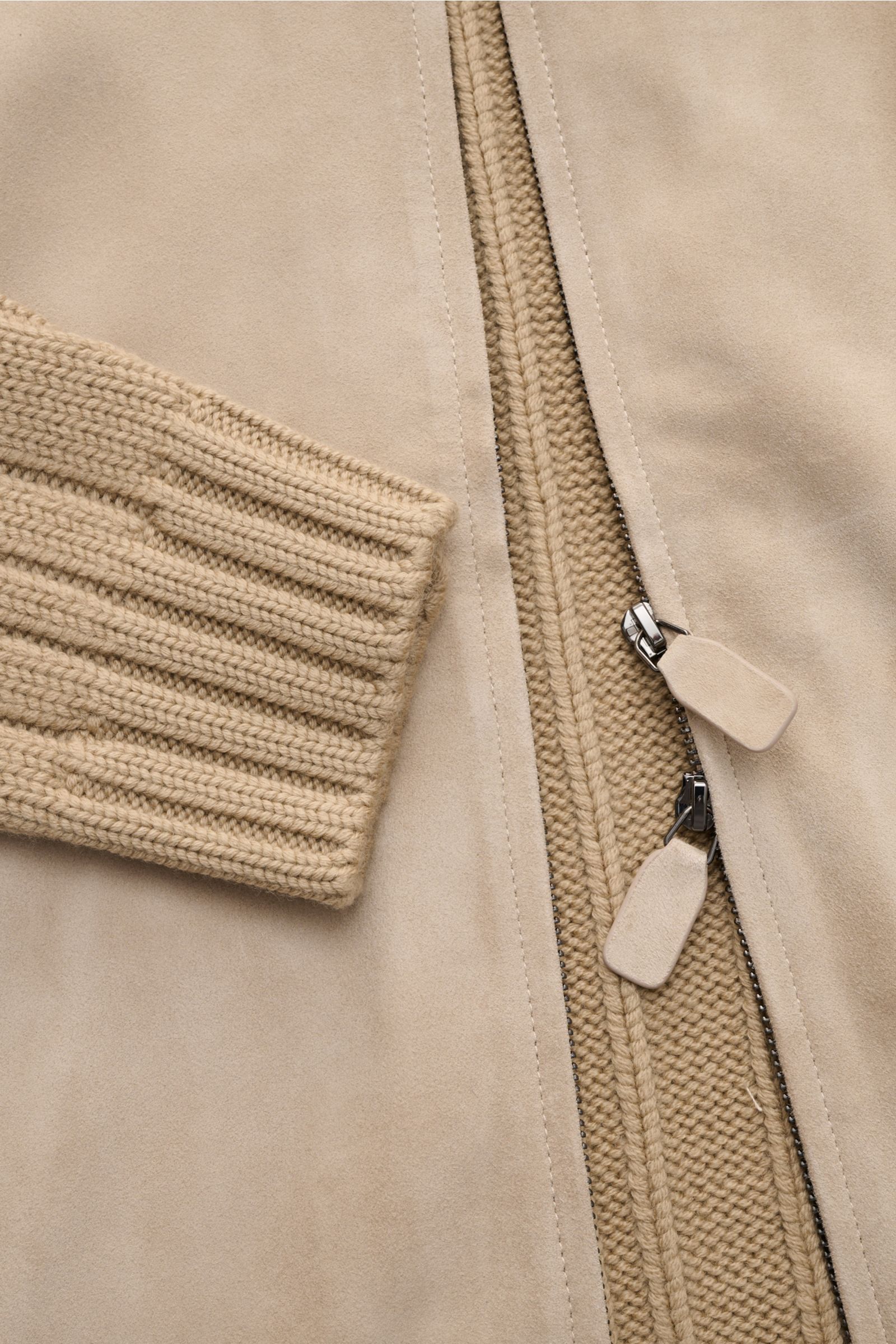 Close-up view of the front section of the Emporio Armani Lederjacke hellbraun, showcasing the soft light brown goat suede leather and chunky knit pure virgin wool. Visible are the concealed two-way zipper with leather pulls, ribbed cuffs, and the textured