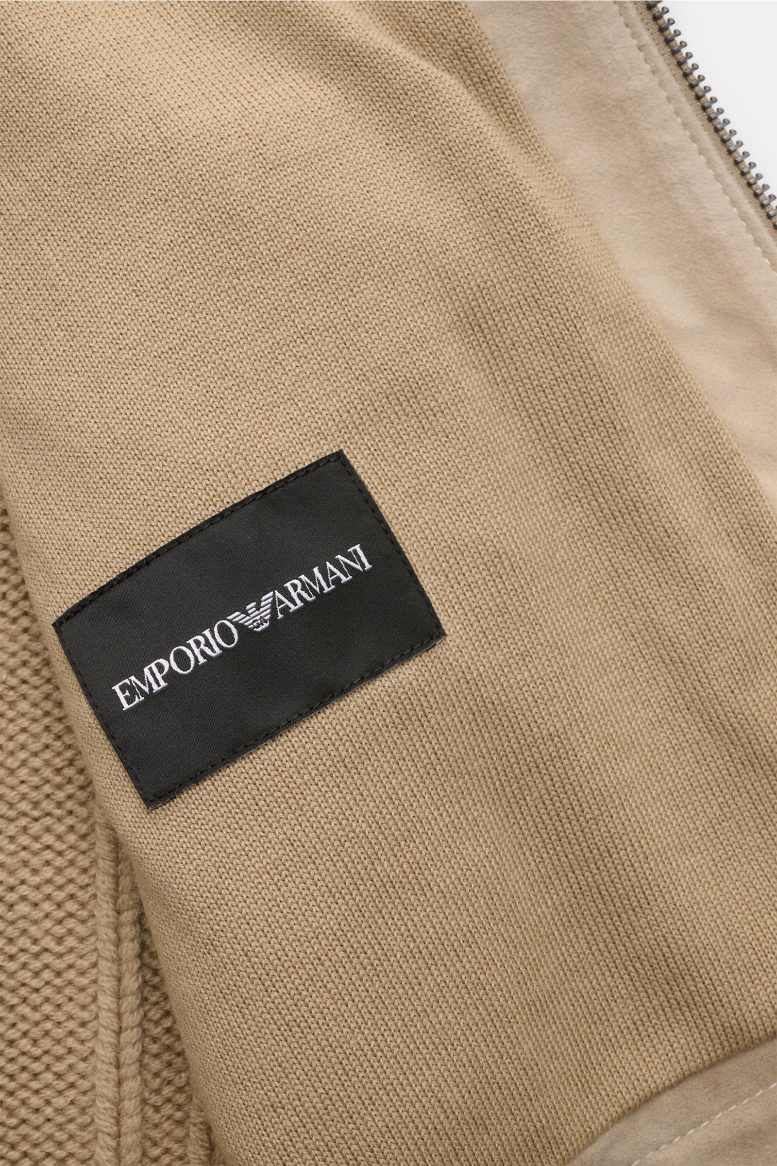 Close-up front view of Emporio Armani Lederjacke hellbraun showing fine wool knit, soft goat suede, and black logo patch.

Description: Ein Hybrid der besonderen Art ist diese Jacke in einer Kombination aus Schurwollstrick und Ziegenveloursleder – stil