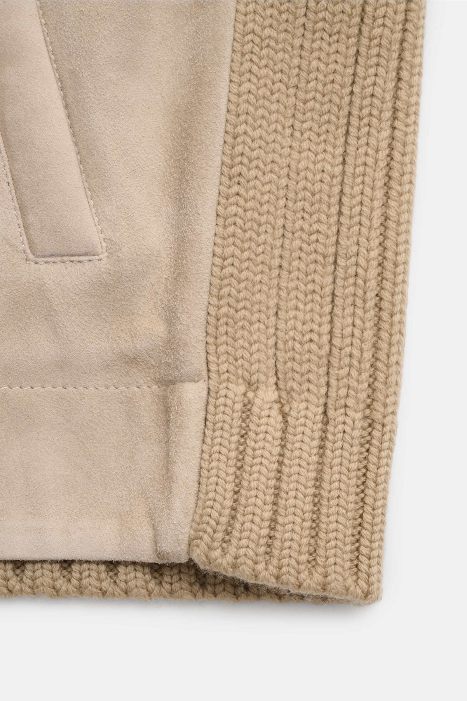 Close-up image of the lower front and sleeve cuff of the Emporio Armani Lederjacke hellbraun, showing the combination of grob knit pure virgin wool with a very soft feel and light padded goat suede leather, photographed from a front-side angle. Ein Hyb