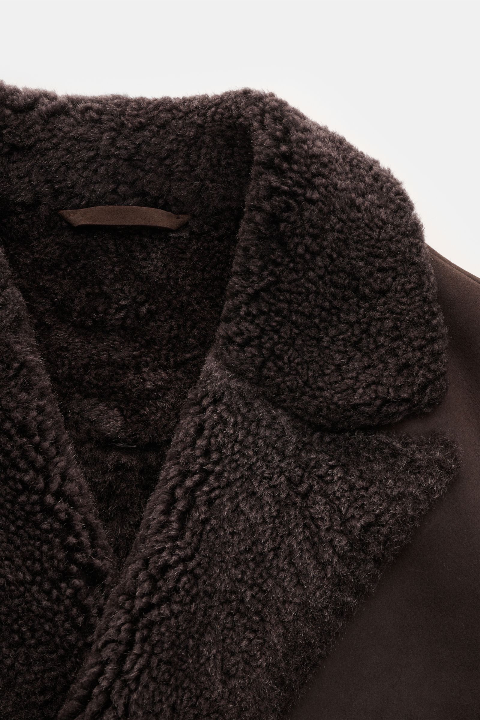 Nahaufnahme des dunkelbraunen Manzoni 24 Lammfellmantels, Fokus auf weiches Lammveloursleder und dickes Lammfell-Revers.