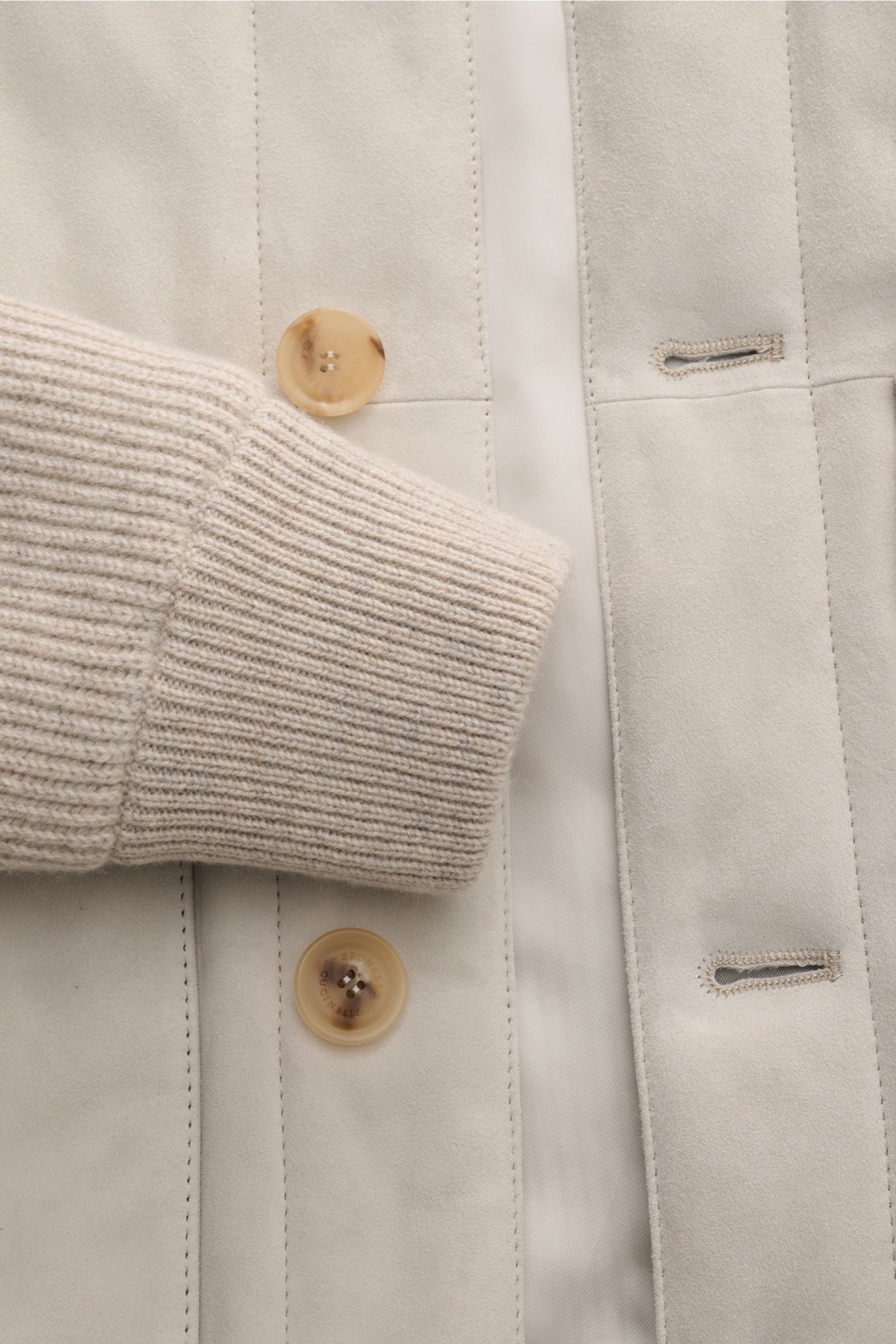 Close-up front view of the Brunello Cucinelli Cashmere Strickblouson braun showing soft beige ribbed cashmere cuff, fine nubuck leather front with two brown buttons and buttonholes, highlighting luxurious materials and craftsmanship. Luxuriöser Cashmer