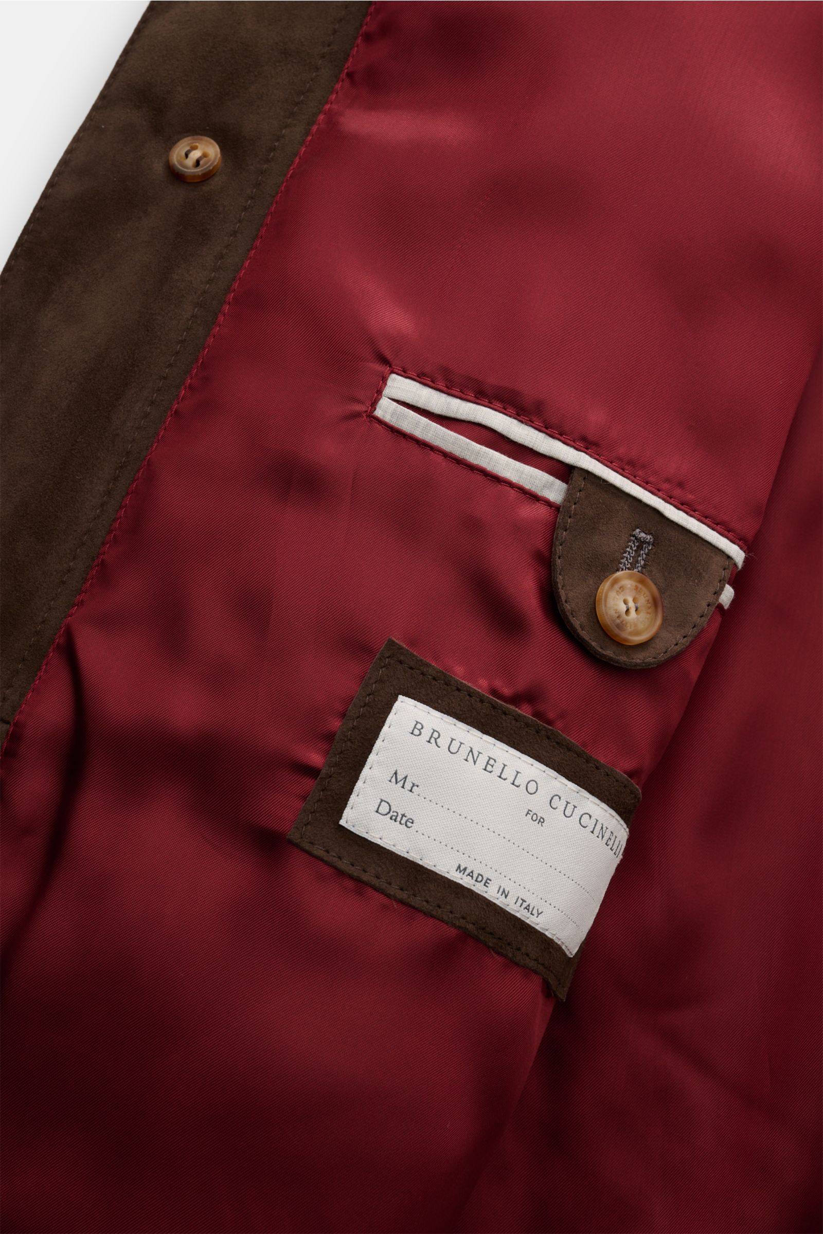 Close-up view of the interior lining of the Brunello Cucinelli Cashmere Strickblouson grau, showing a smooth burgundy fabric with a buttoned inner pocket and a label. Luxurious cashmere knit meets fine nubuck leather in this elegant slim fit blouson with 