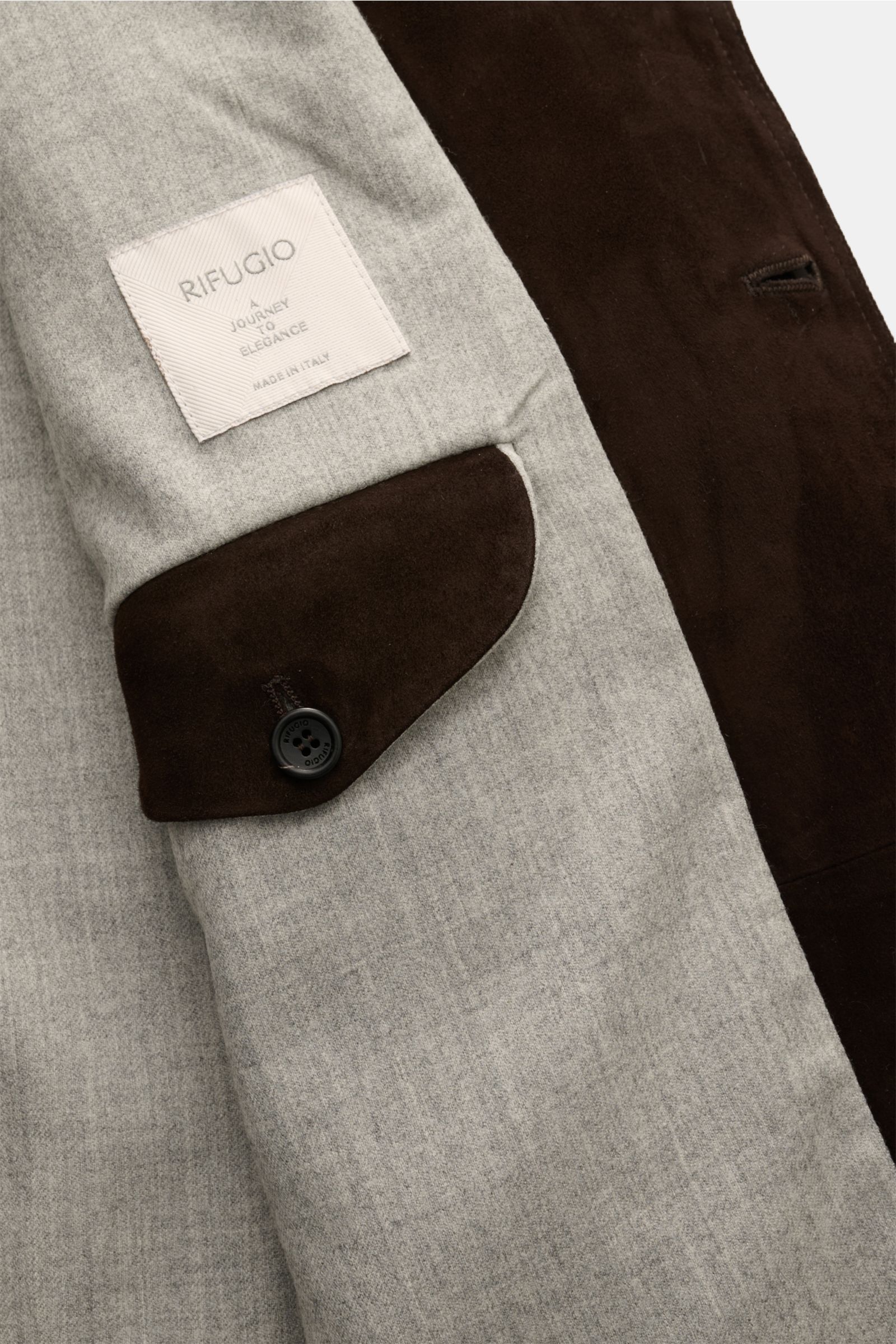 Rifugio Velourslederjacke dunkelbraun von innen fotografiert, zeigt weiches Wollfutter, Manschette mit Knopf und RIFUGIO-Label.