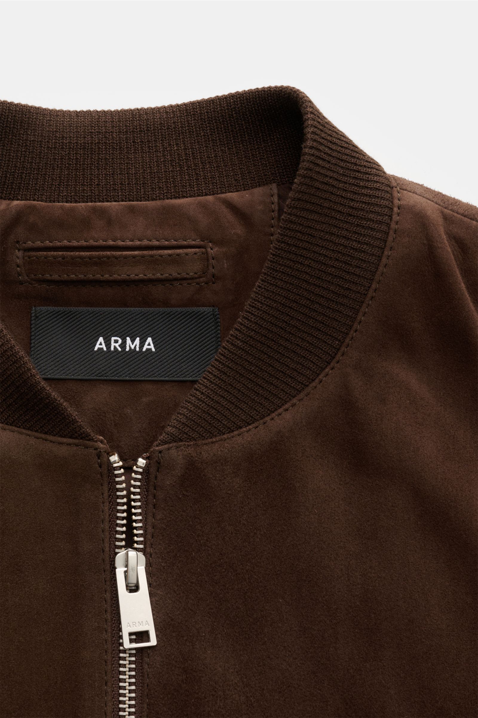 Close-up front view of Arma Suede blouson 'Didier' brown showing its fine goat suede texture, ribbed collar, and robust two-way zip.

Smart and timeless: The leather blouson 'Didier' from ARMA is made of supple goat suede and stands out with a striking