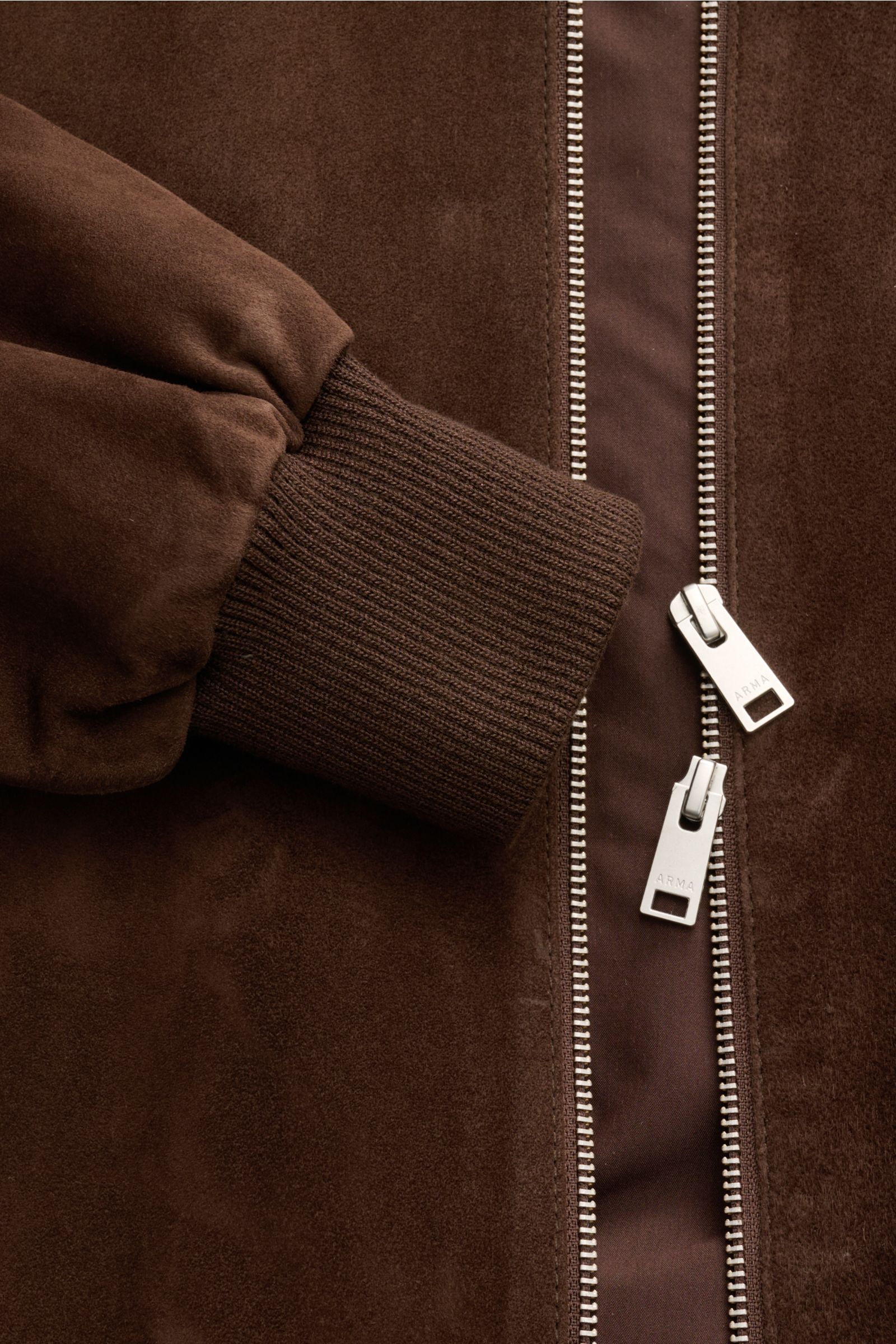 Close-up front-side view of Arma Suede blouson 'Didier' brown showing supple goat suede, elastic ribbed cuff, and robust two-way zip with ARMA branding.

Smart and timeless: The leather blouson 'Didier' from ARMA is made of supple goat suede and stands