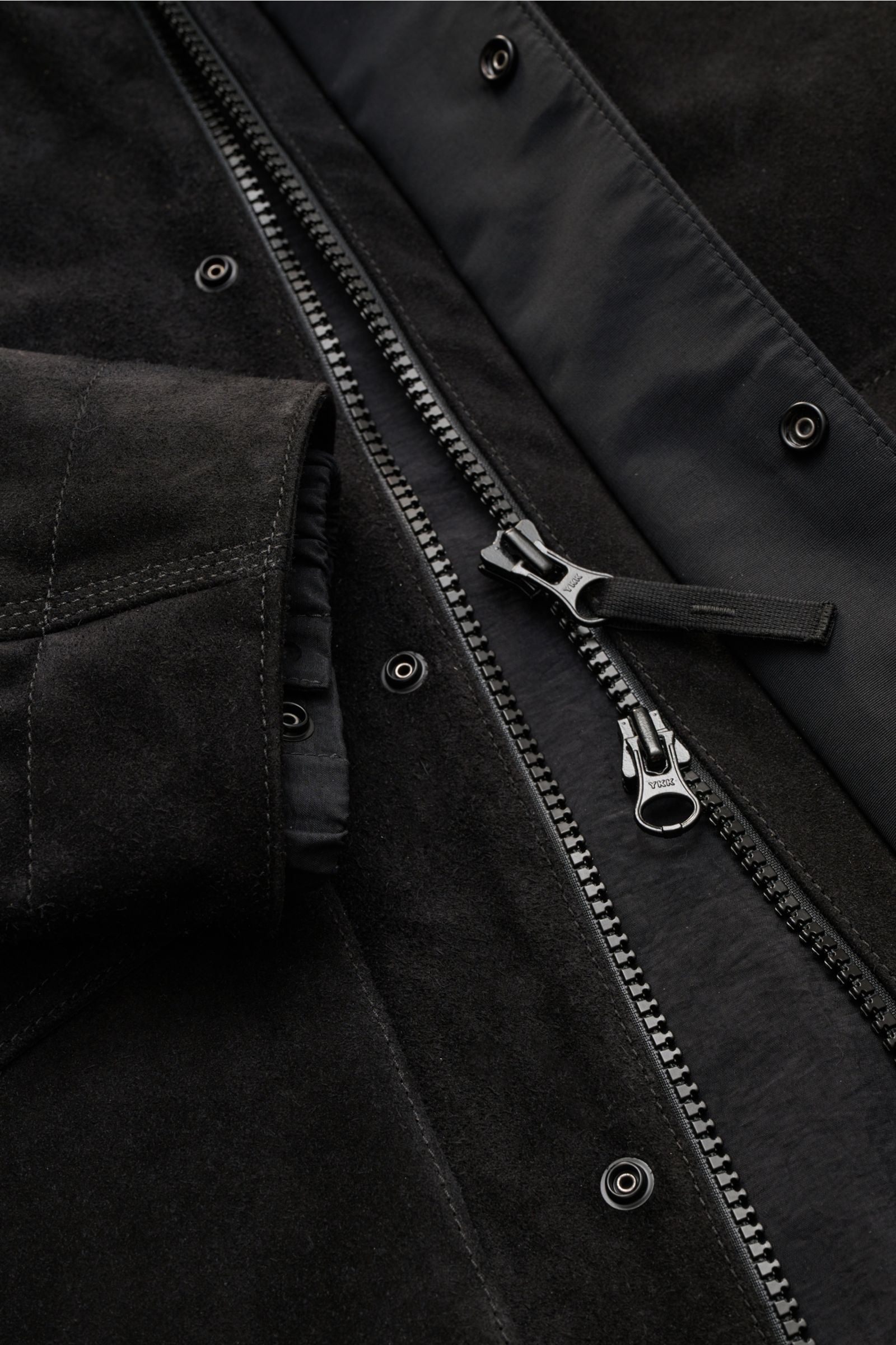 Stone Island Velourslederjacke 'Ghost Piece' schwarz, Nahaufnahme von Reißverschluss, Druckknöpfen, elastischem Ärmelbündchen und weichem Veloursleder.