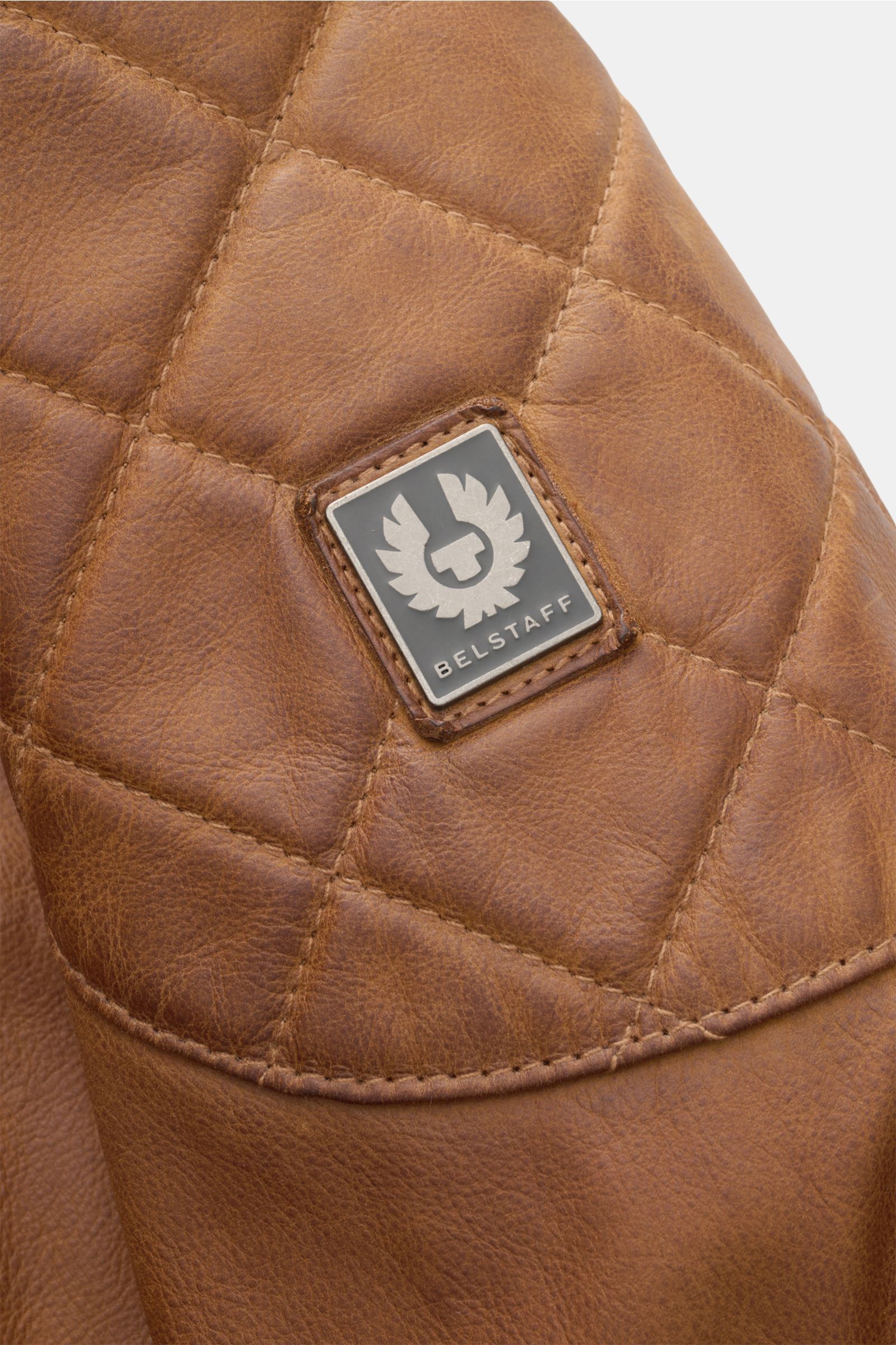 Nahaufnahme der Belstaff Lederjacke 'Legacy Outlaw' braun, handgewachstes, wasserabweisendes Kalbleder mit gestepptem Oberarm und Metall-Logo.