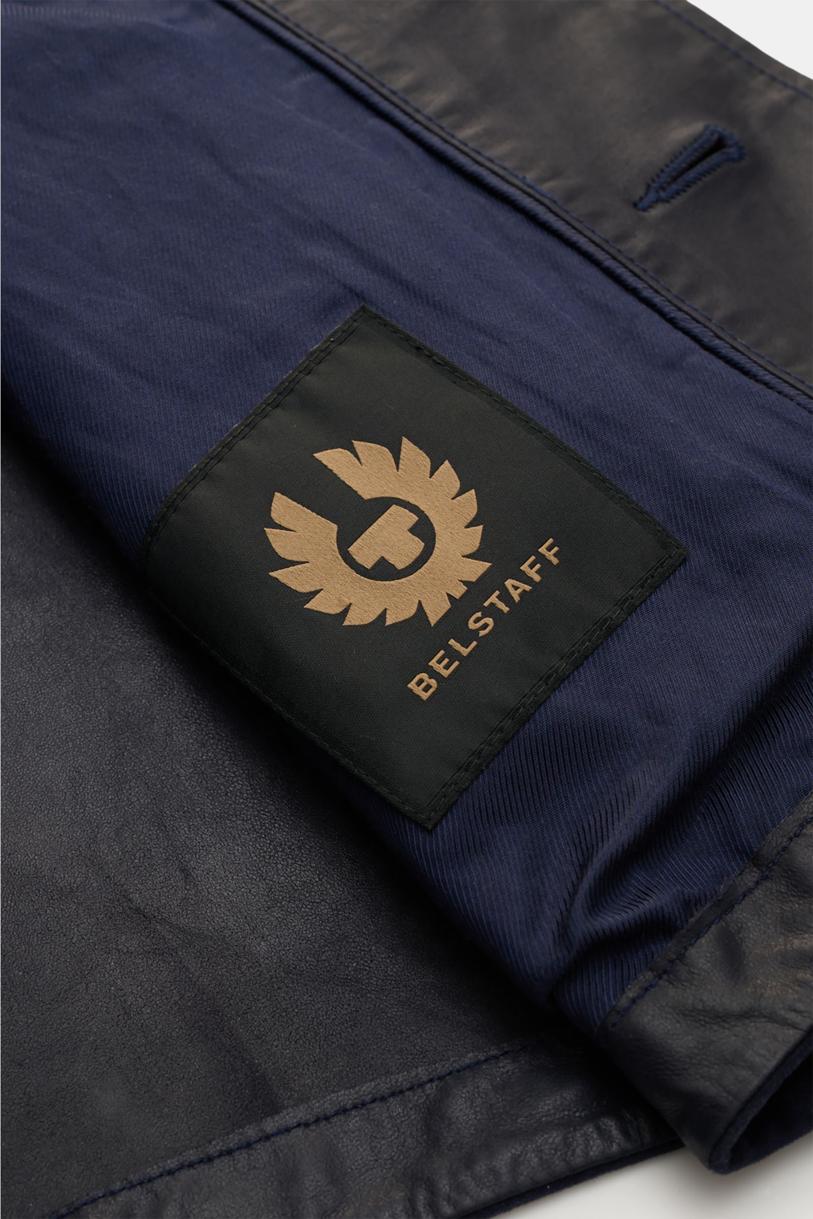 Close-up inside view of the Belstaff Suede jacket 'Waymark' navy showing the black and gold BELSTAFF label on supple navy suede with tonal lining.

Description:  
A versatile piece in supple suede: The hybrid 'Waymark' by BELSTAFF is a cool alternative
