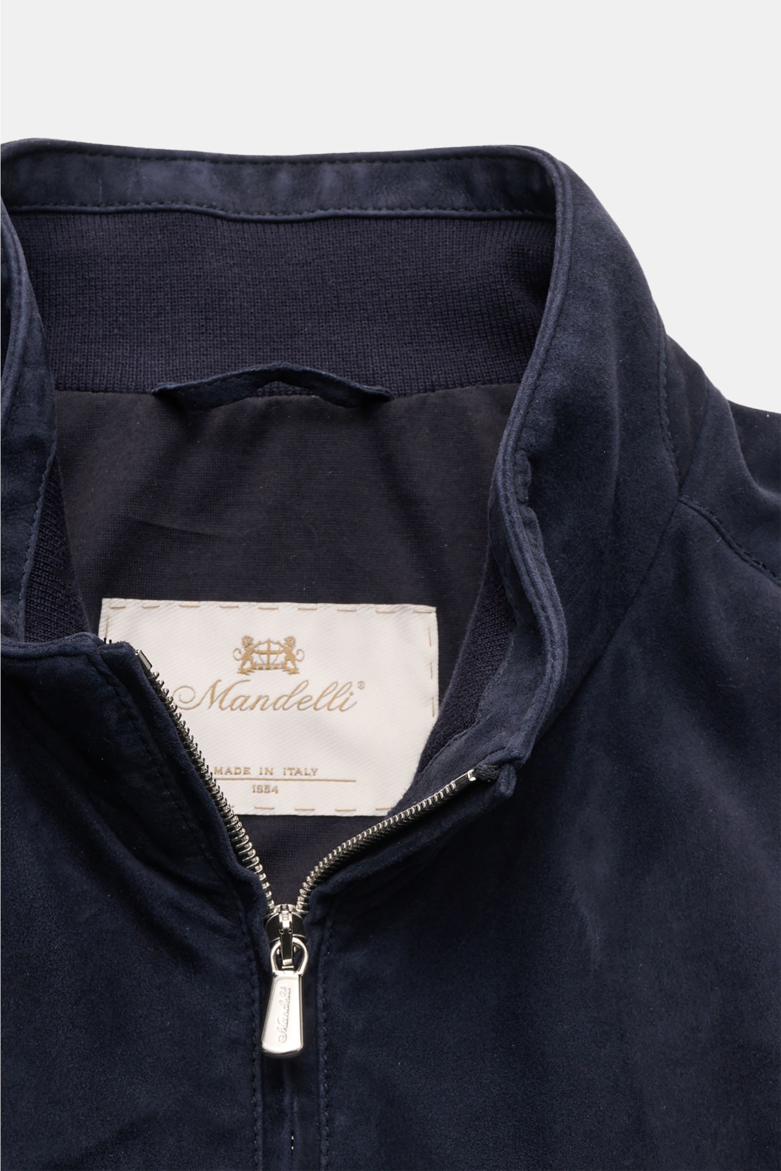 Nahaufnahme des Mandelli Veloursleder-Blouson navy von oben, zeigt hoch schließenden Stehkragen aus Ziegen-Veloursleder mit Zwei-Wege-Reißverschluss, elastische Bündchen, slim fit und weiche Haptik, ungefüttert, lässig und elegant für die Übergangszeit.