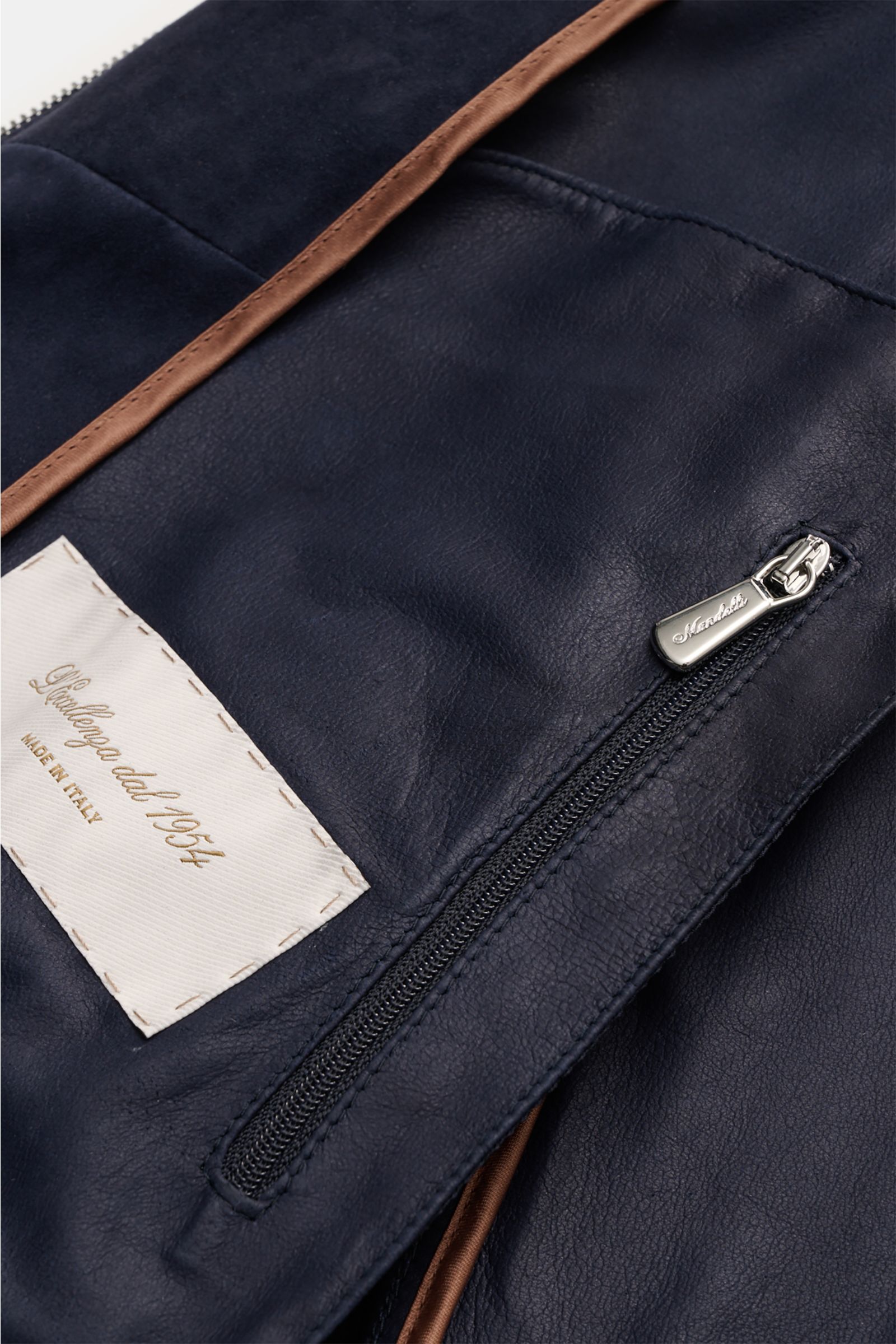 Nahaufnahme des Mandelli Veloursleder-Blouson navy von innen, zeigt Ziegen-Veloursleder, Innentasche mit Reißverschluss, braune Paspel und Label.