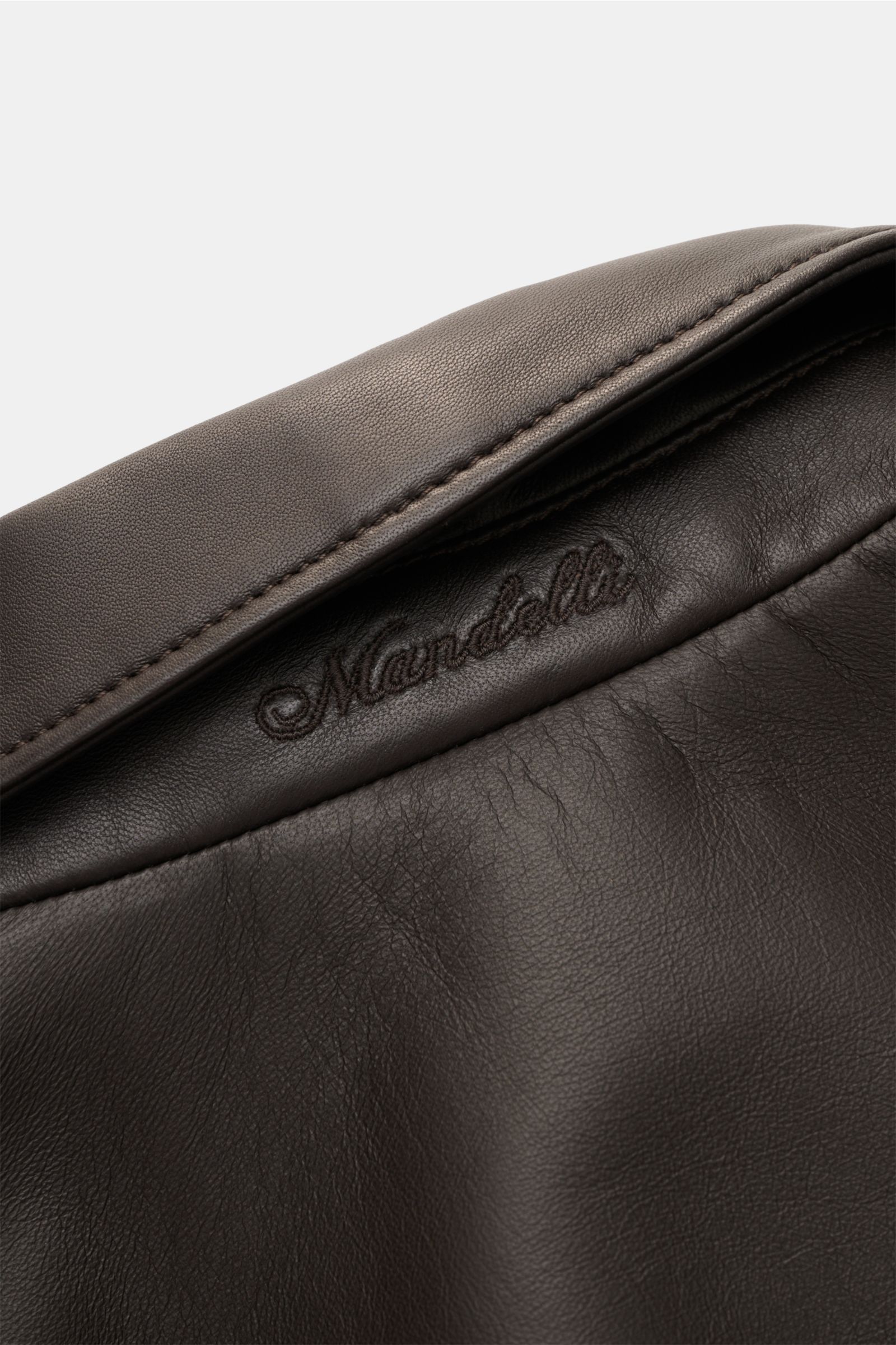 Nahaufnahme des Mandelli Lederblouson dunkelbraun von oben, zeigt glattes, geschmeidiges Lammleder und feine Nahtdetails.