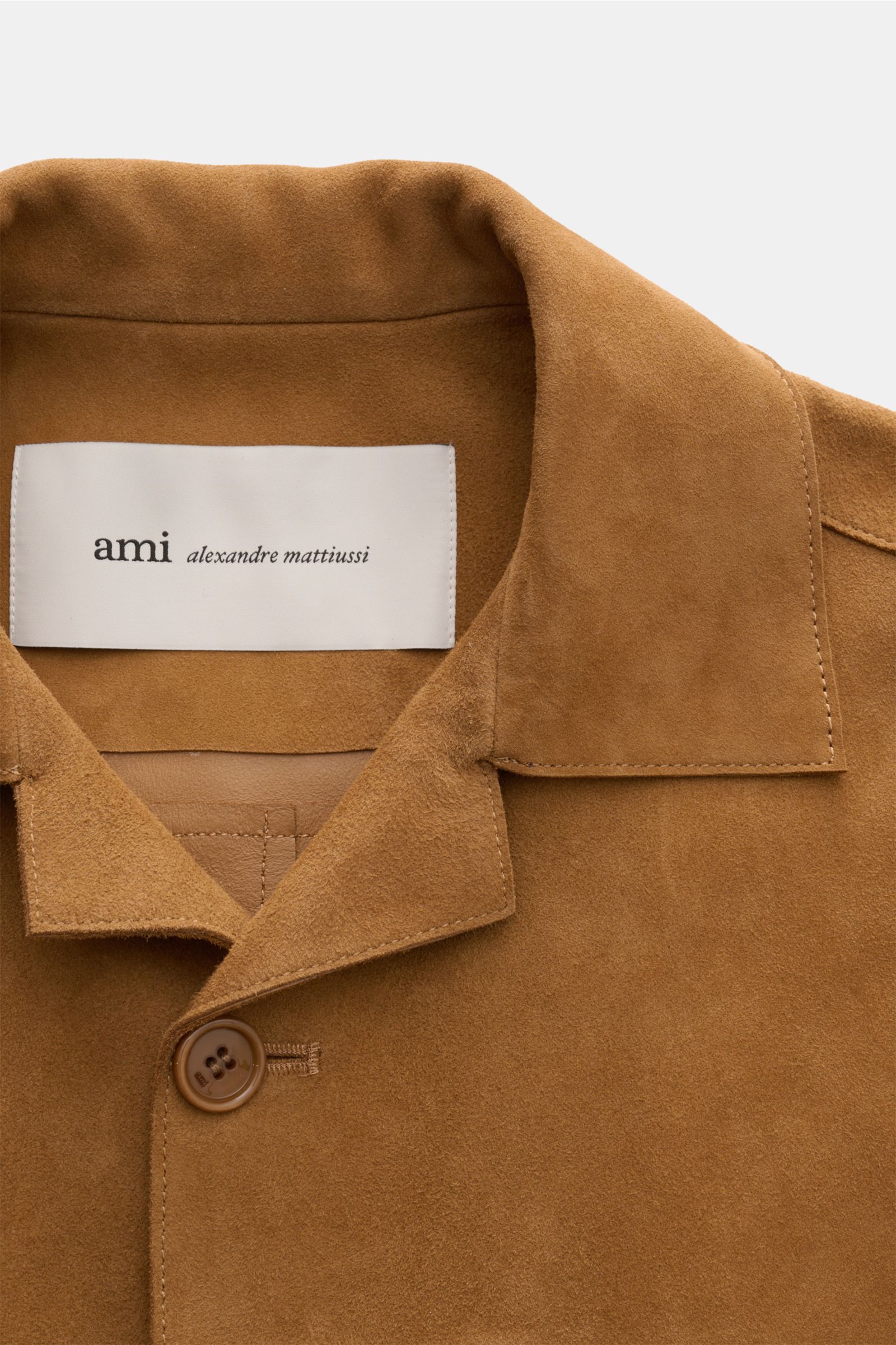 Close-up front view of Ami Paris Veloursleder-Overshirt camel showing soft velours leather, short collar, single button, and stitching details. Urban und lässig: Dieses Overshirt aus edlem Veloursleder von AMI PARIS ist ein Hingucker und lässt sich perfek