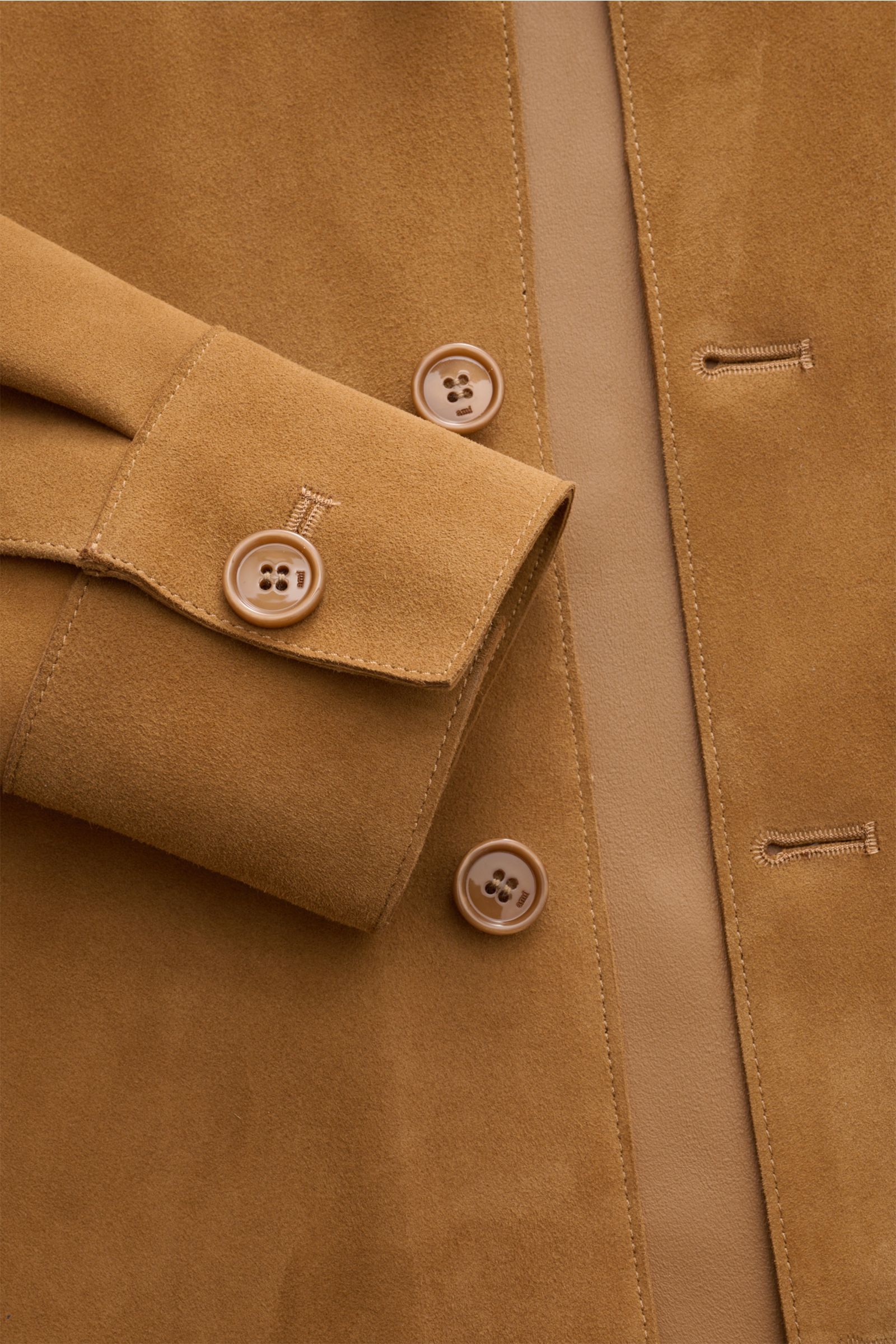 Close-up front view of Ami Paris Veloursleder-Overshirt camel showing soft camel suede, oversized cuff with button, five-button placket, and detailed stitching, featuring soft Veloursleder, soft grip, oversized fit, short notch collar, patch chest pocket,