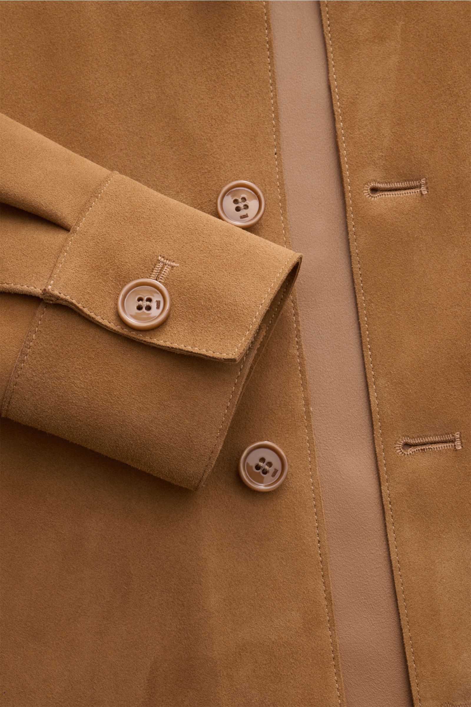 Close-up view of the Ami Paris Veloursleder-Overshirt camel showing soft suede texture, button cuff, five-button placket, and precise stitching. Urban und lässig: Dieses Overshirt aus edlem Veloursleder von AMI PARIS ist ein Hingucker und lässt sich perfe