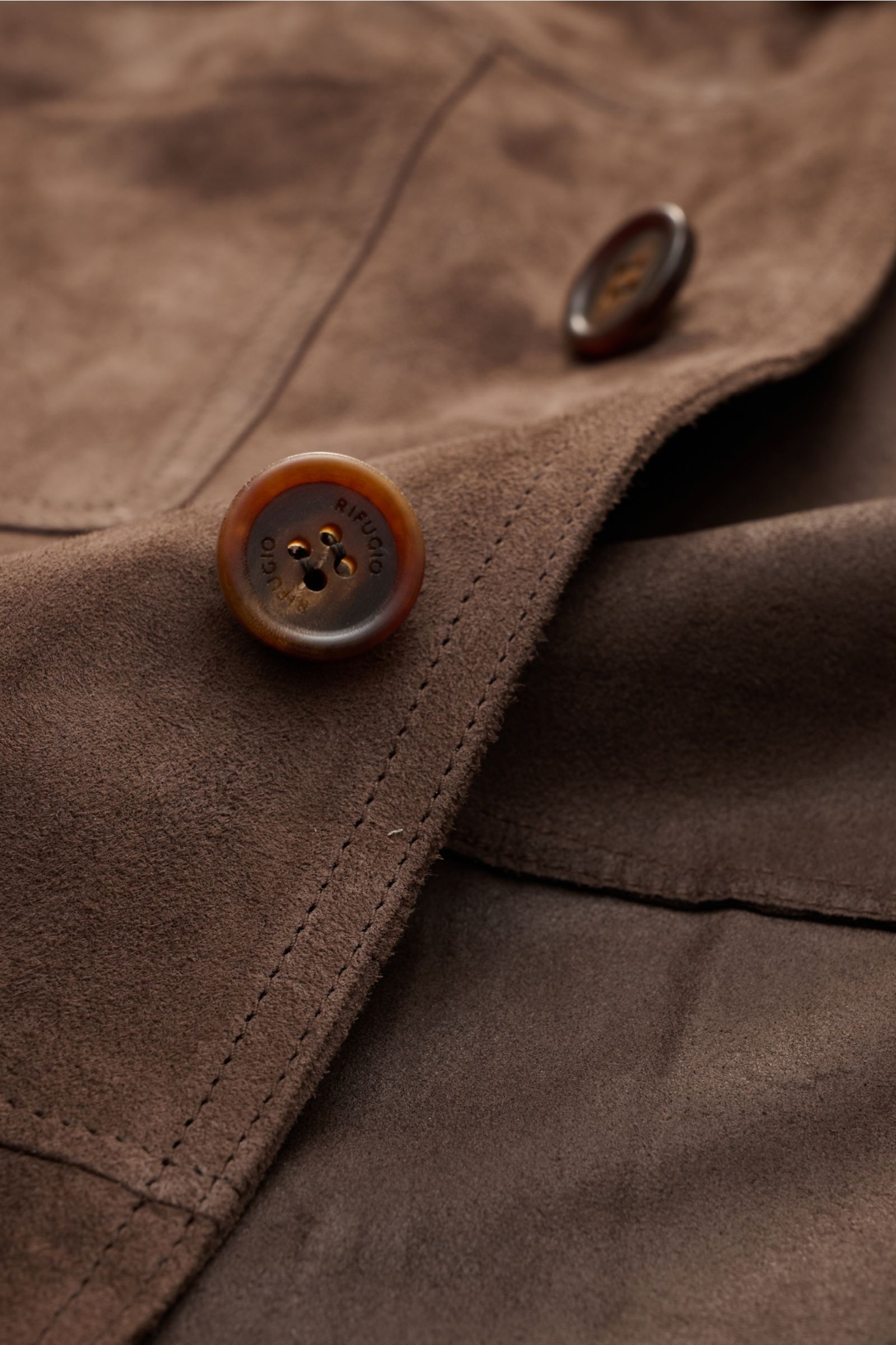 Close-up front detail of Rifugio Suede jacket dark brown showing supple suede, five-button placket, and soft texture from a top-down perspective.