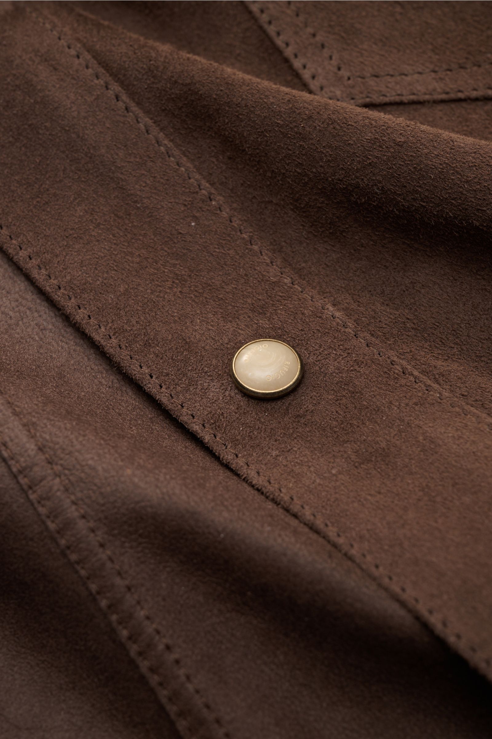 Nahaufnahme der Rifugio Velourslederjacke dunkelbraun aus feinstem Lammvelours mit weichem Griff, Slim Fit, Druckknopf und sichtbarer Naht.