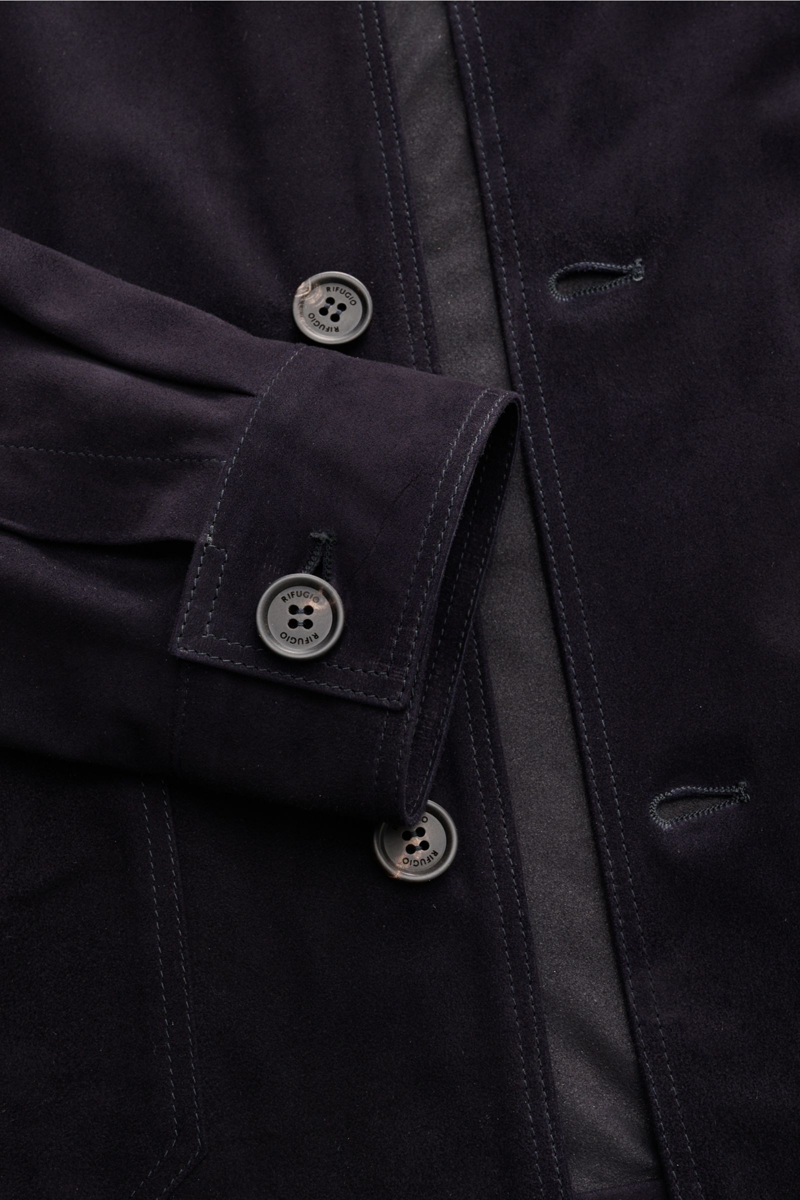 Close-up front view of Rifugio Suede jacket dark navy showcasing smooth suede, five-button placket, turn-down collar, patch pockets, cuffs, and unconstructed design. Confident elegance meets exquisite workmanship in this slim-fit, velvety-soft leather jac