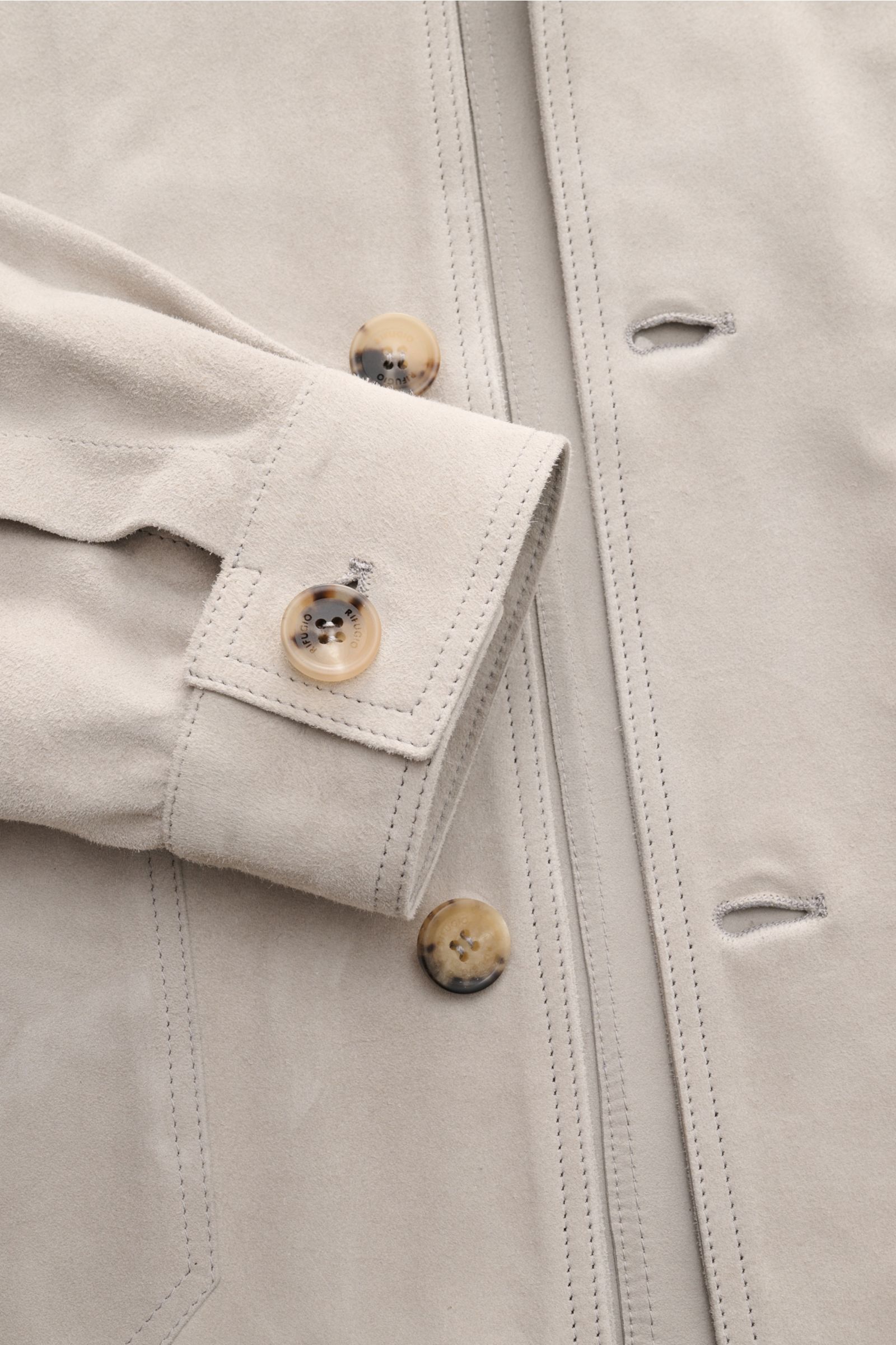 Rifugio Suede jacket light grey shown from a close-up front angle, highlighting smooth suede, five-button placket, turn-down collar, patch pockets, cuffs, and detailed stitching. Confident elegance meets exquisite workmanship: This suede jacket by RIFUGIO
