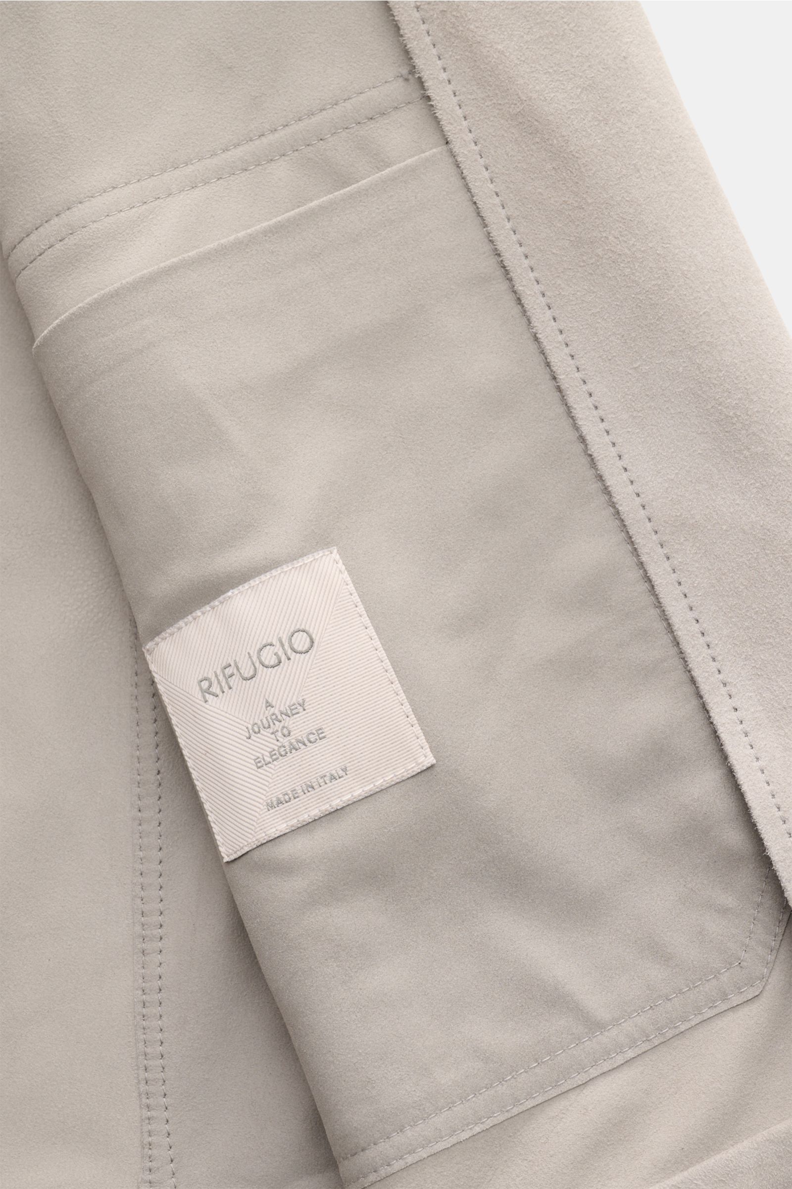 Close-up interior view of the Rifugio Suede jacket light grey showing smooth suede, soft feel, and label. Confident elegance meets exquisite workmanship in this slim fit jacket with a five-button placket, turn-down collar, patch front pockets with flap, s