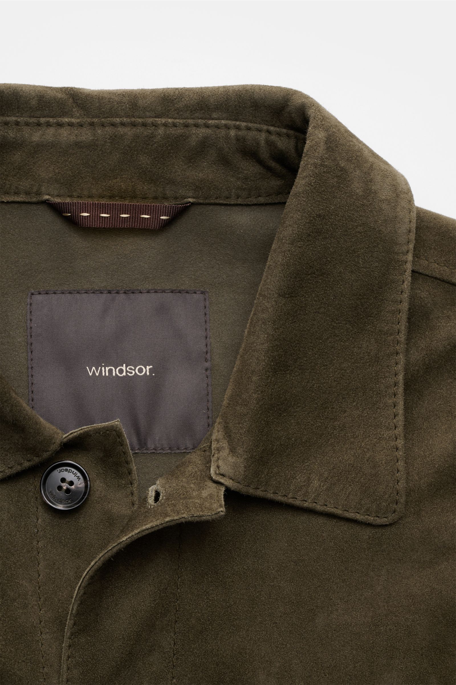 Nahaufnahme der Windsor Velourslederjacke 'Olfano' dark olive von oben, zeigt weiches Ziegenvelours, Umlegekragen, Knopf und Label.