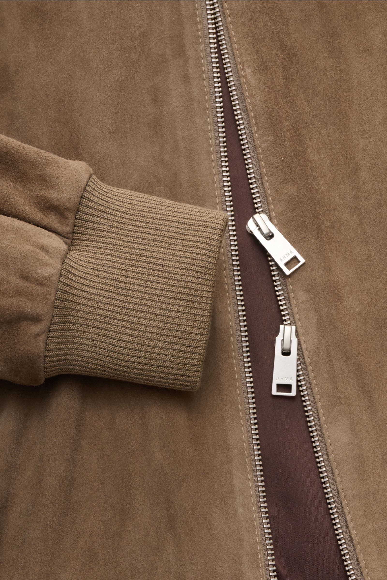 Nahaufnahme des Arma Veloursleder-Blouson 'Didier' taupe von schräg oben, zeigt feines Ziegenvelours, elastisches Rippbündchen und robusten Zwei-Wege-Zipper.