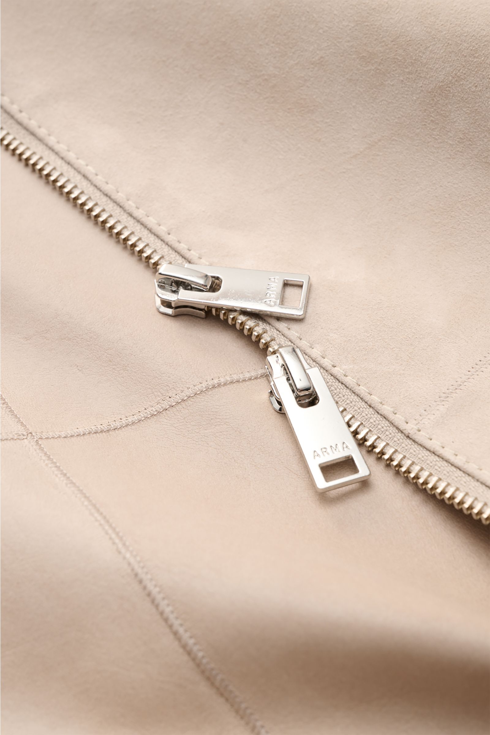 Nahaufnahme des robusten Zwei-Wege-Zippers am sandfarbenen Arma Veloursleder-Blouson 'Dion' aus feinem Ziegenvelours, ungefüttert.