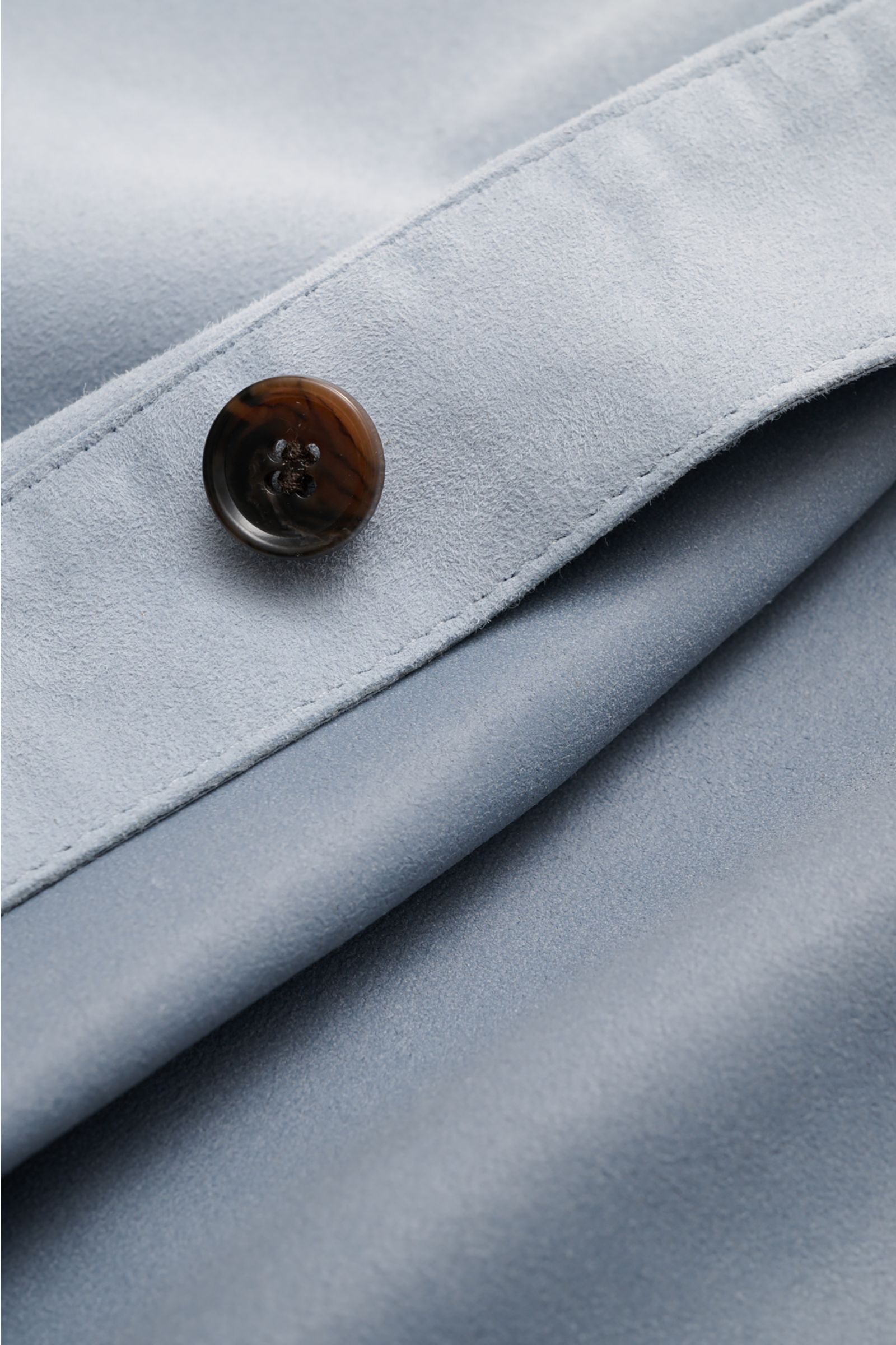 Nahaufnahme des Knopfs an der Ärmelmanschette der Arma Velourslederjacke 'Dino' rauchblau aus softem Veloursleder mit weichem Griff.