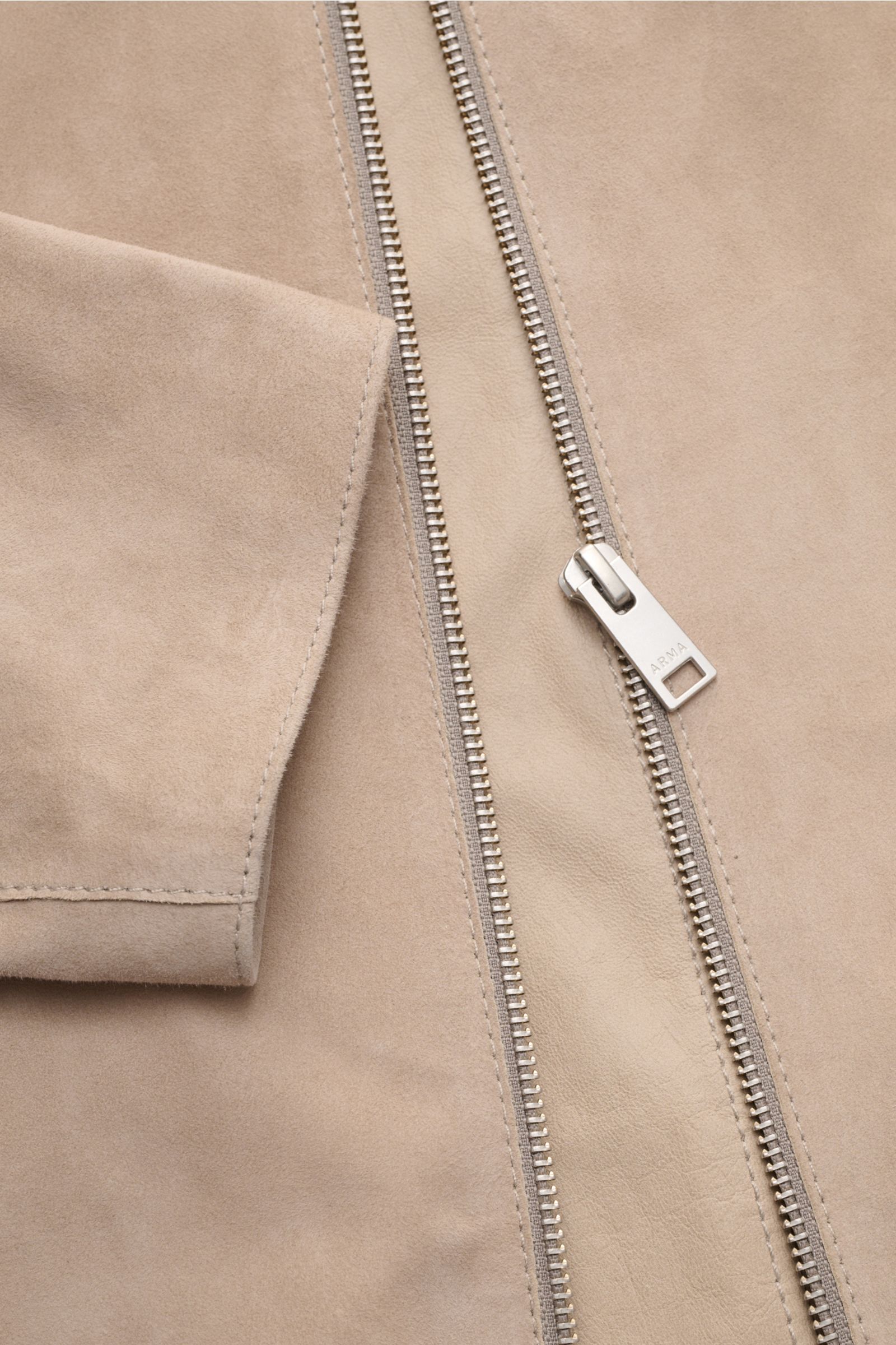 Nahaufnahme der Arma Velourslederjacke 'Hardin' beige, schräg von oben, zeigt weiches Ziegenvelours, Metall-Reißverschluss und Leistentasche.