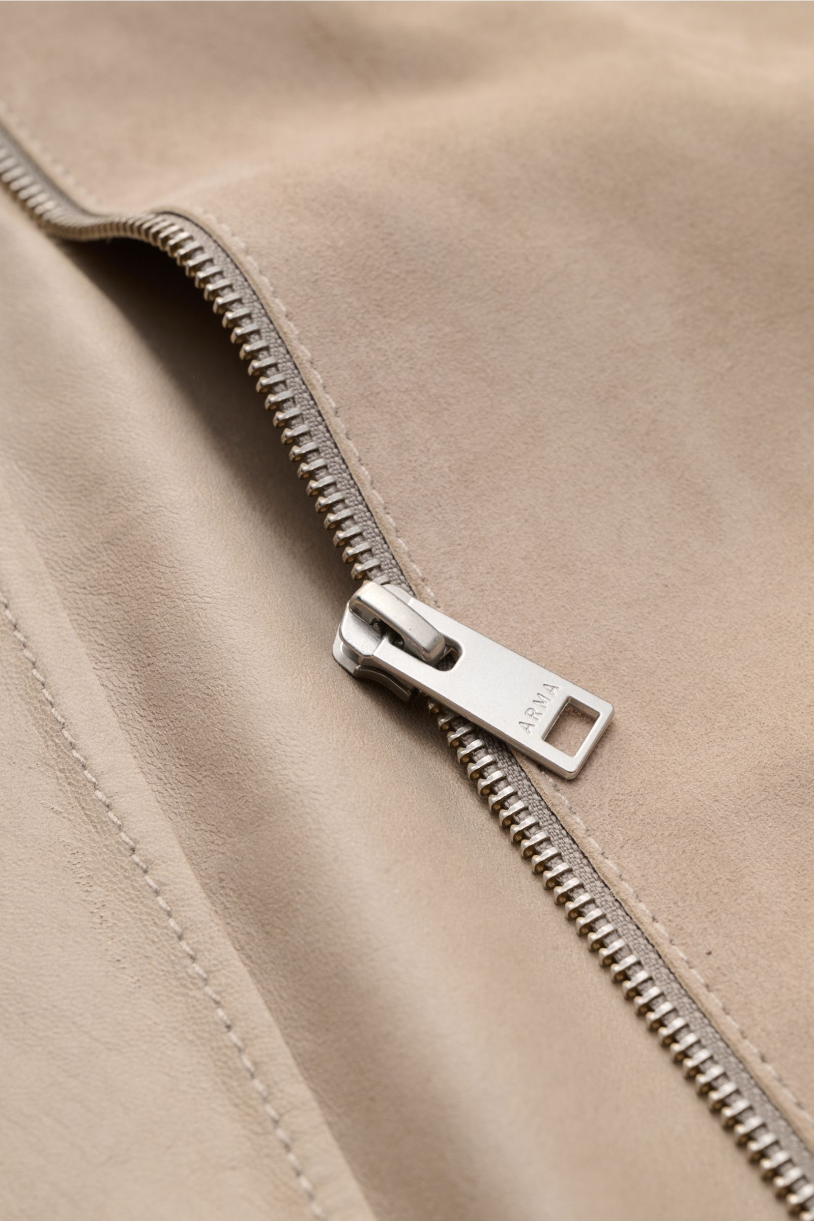 Nahaufnahme der Arma Velourslederjacke 'Hardin' beige, von oben fotografiert, zeigt geschmeidiges Ziegenveloursleder mit robustem Metall-Reißverschluss.