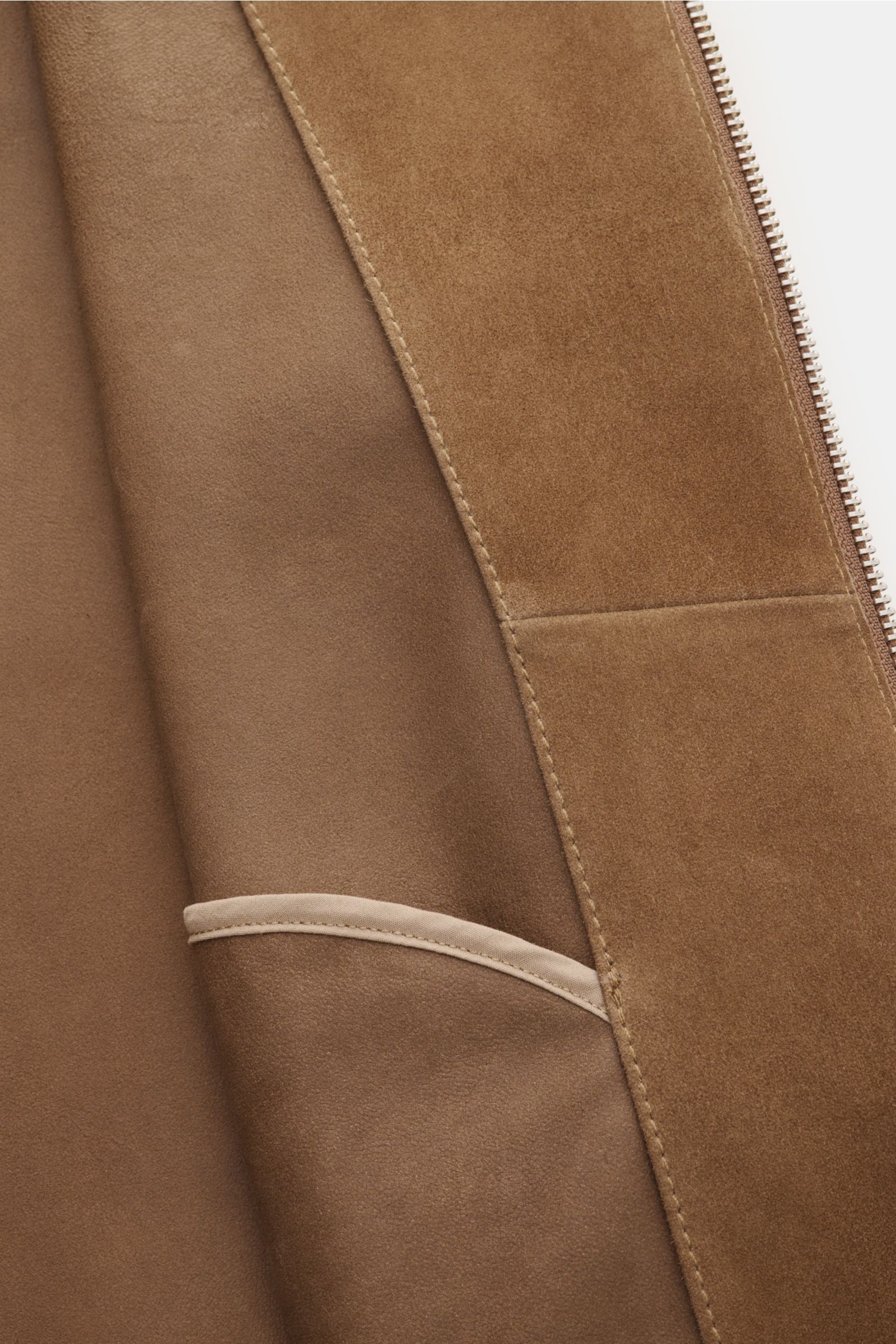 Close-up interior view of the Arma Velourslederjacke 'Masis' hellbraun showing smooth goatskin suede, soft grip, slim fit, robust metal zipper, fold collar, slanted welt pockets with snap button, ribbed cuffs and hem, and unconstructed design.