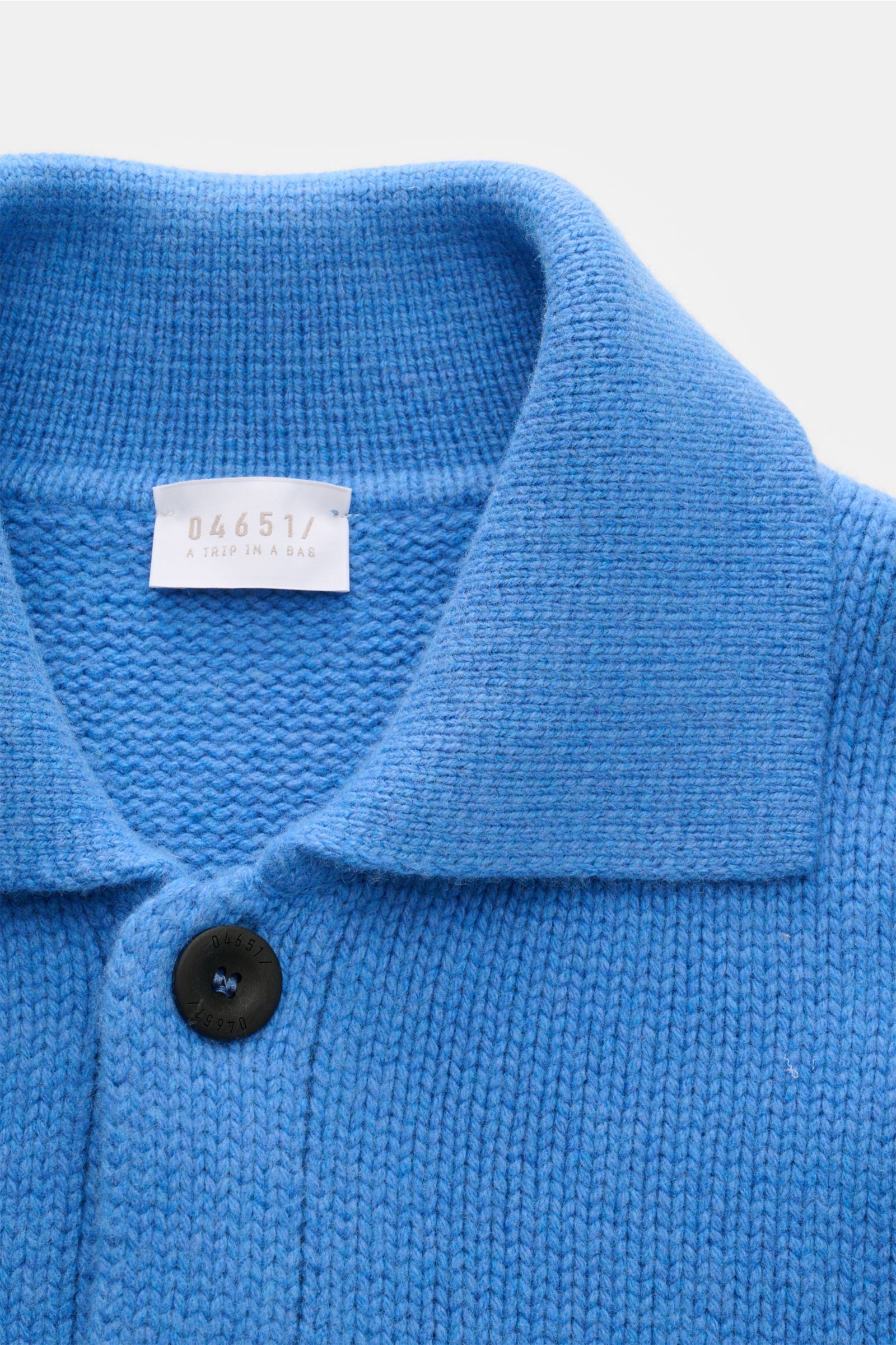 Nahaufnahme aus schräger Perspektive des blauen 04651/ A trip in a bag Cardigan 'Boiled Blouson' mit Umlegekragen, sechs-Knopf-Leiste, Rippbündchen, gestrickt aus schwerer Wolle, Cashmere und Microfaser.